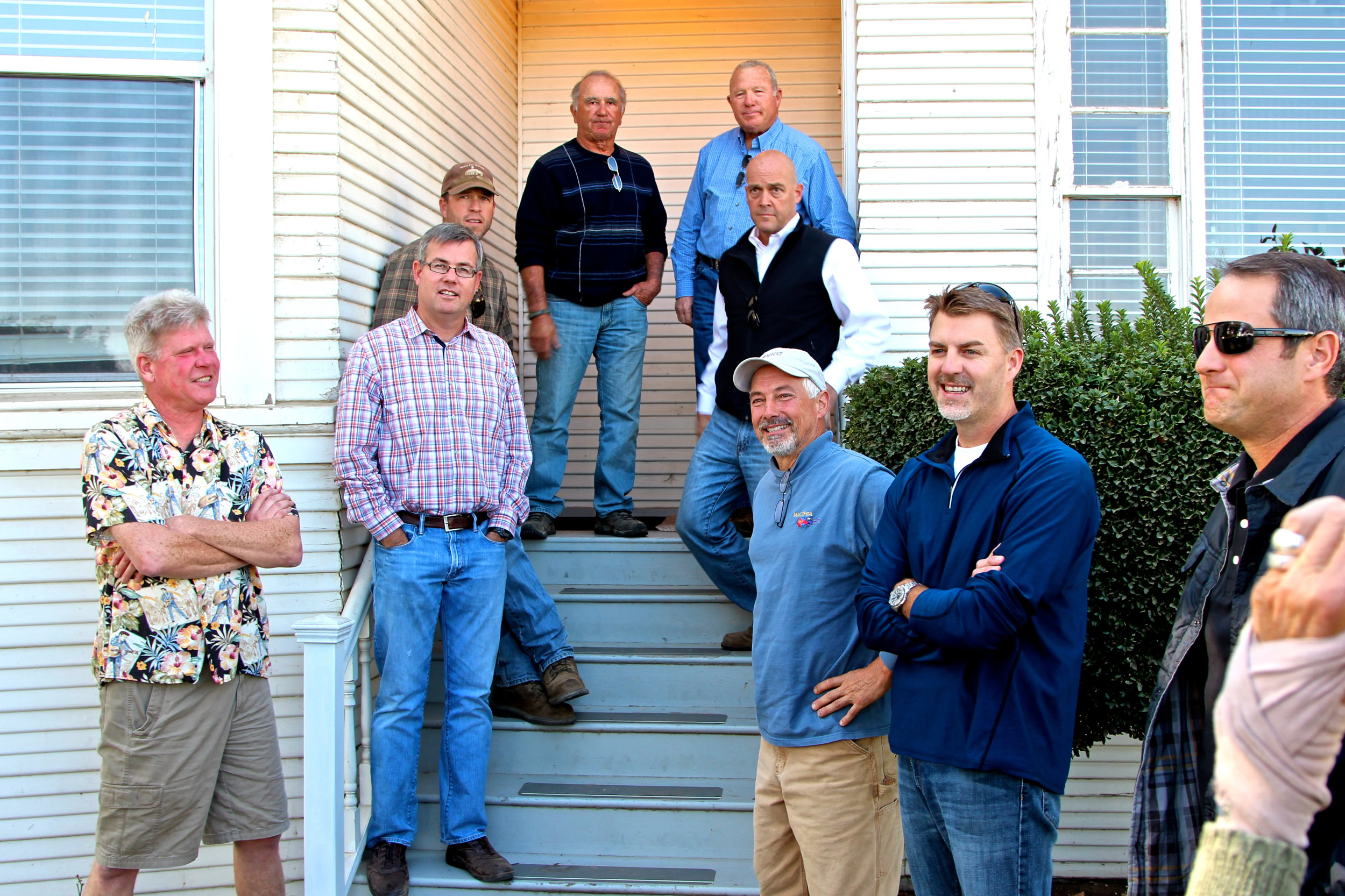 Group of men standing on steps outside a house, discussing wine grape cultivation in Lodi, California.
