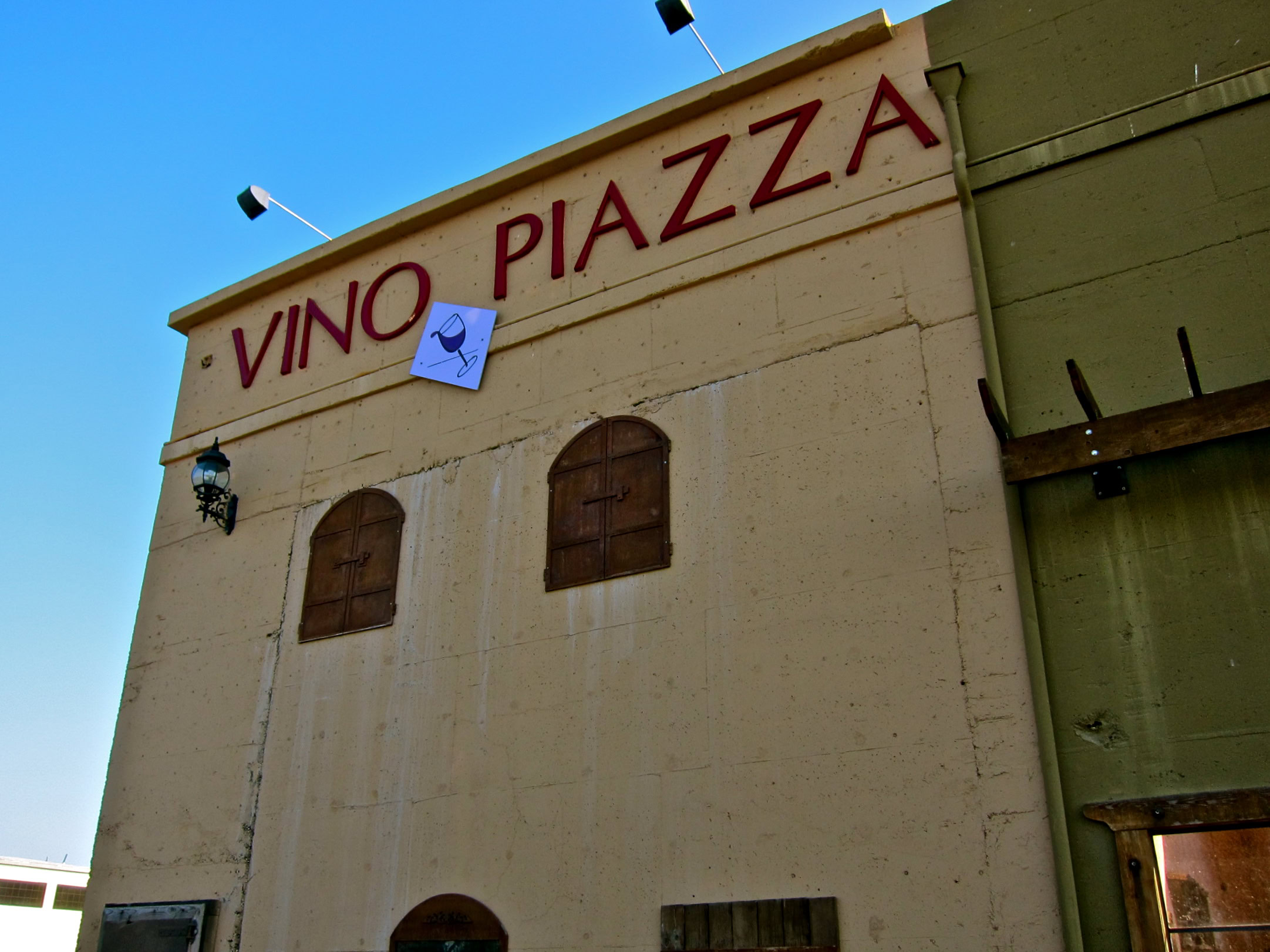 Vino Piazza building with wine-related signage in Lodi, California, under a clear blue sky.
