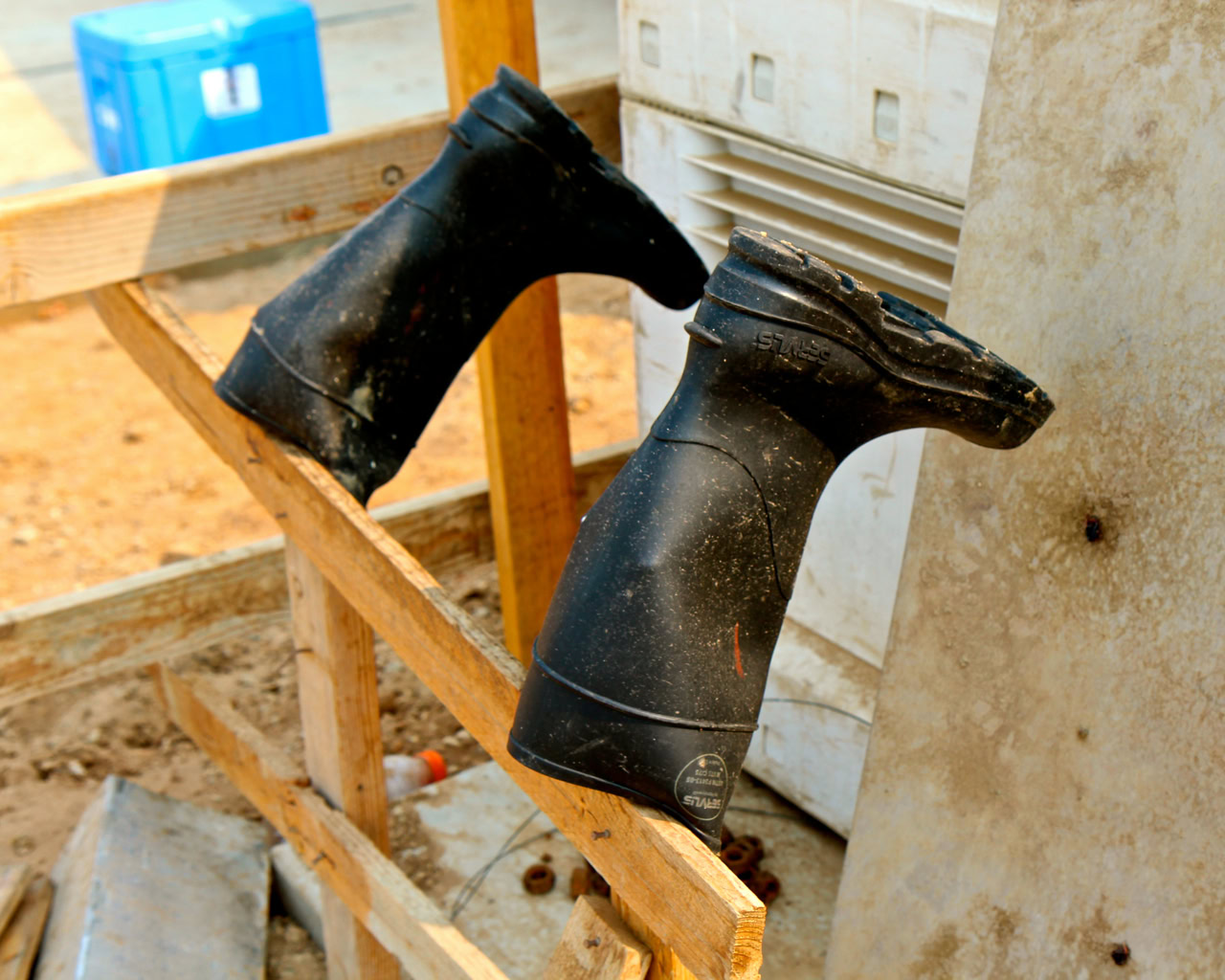 Black rubber boots placed on a wooden frame at a vineyard site in Lodi, California.