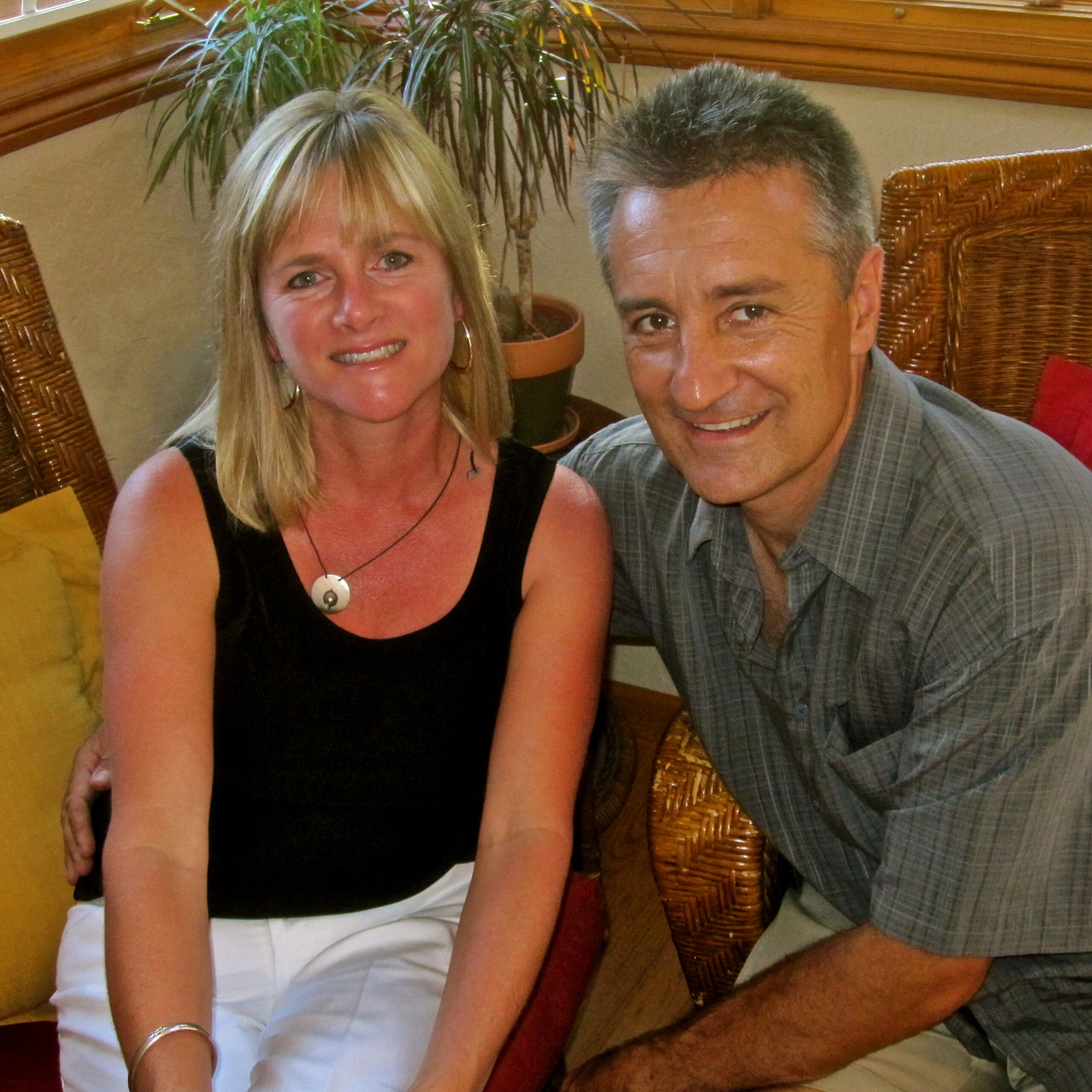 Two smiling individuals at a Lodi Winegrape Commission event, sitting indoors with plants and wicker furniture.