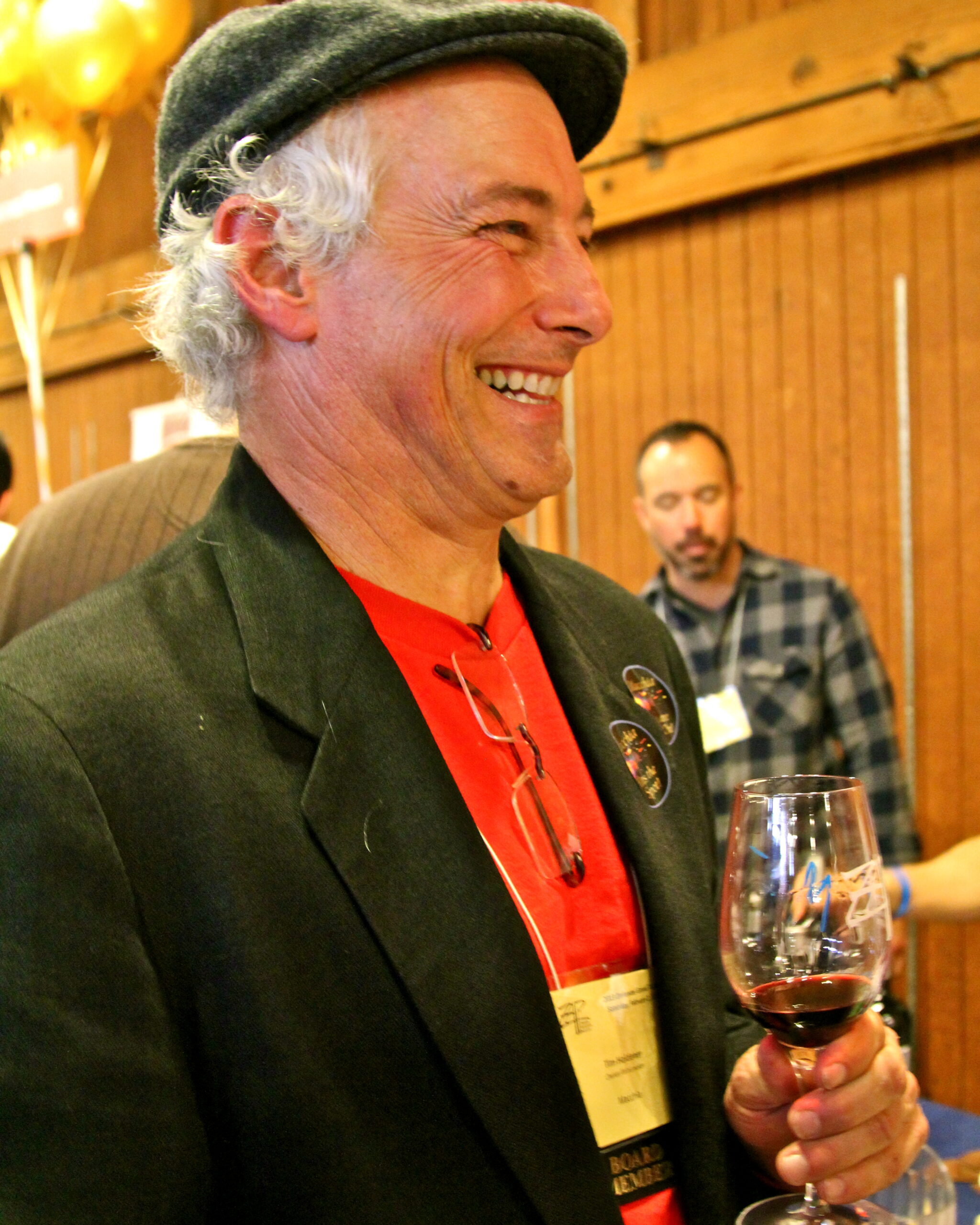 Smiling man at Lodi Winegrape Commission event holding a glass of red wine.