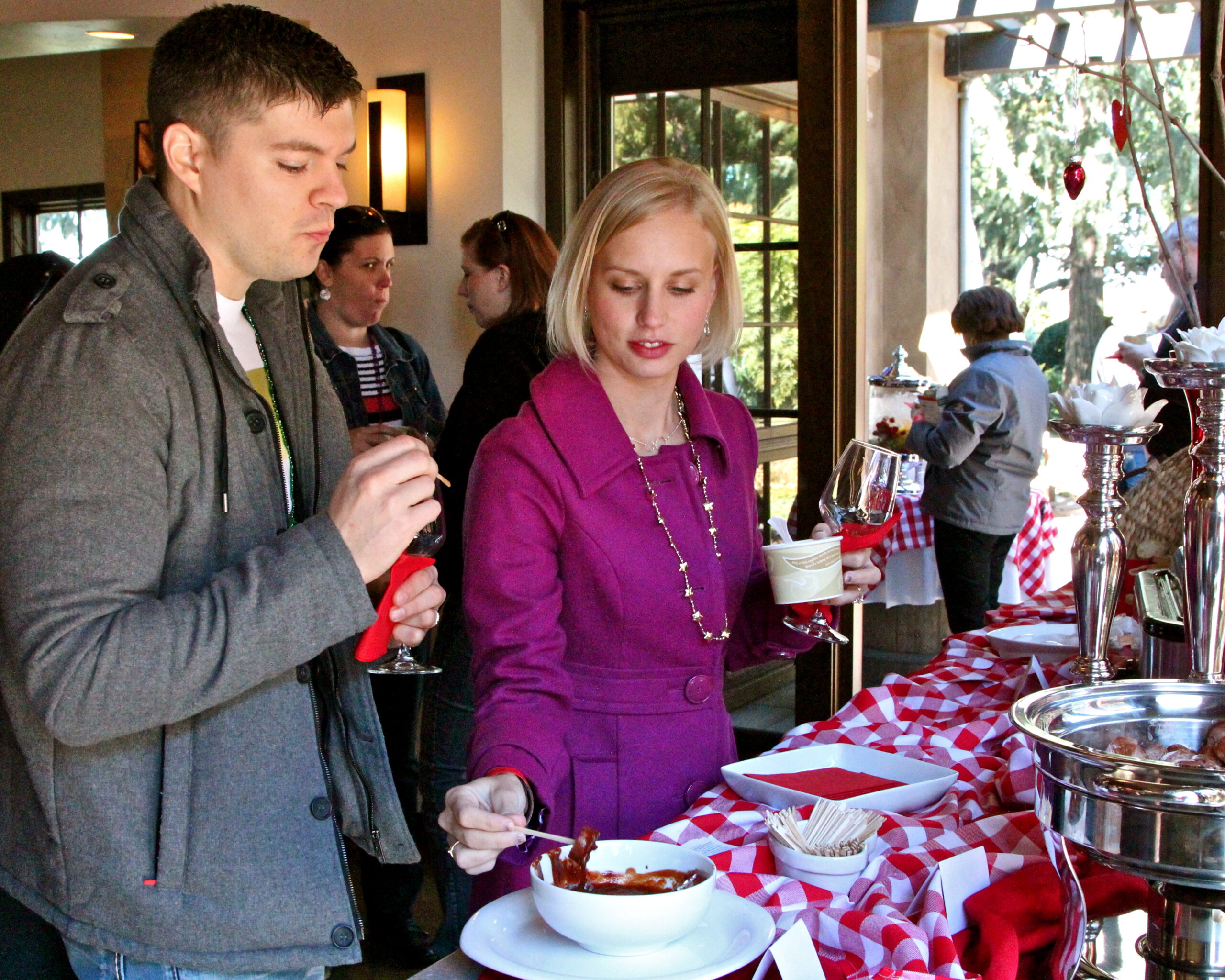 People enjoying wine tasting at a Lodi Winegrape Commission event with a buffet table and wine glasses.