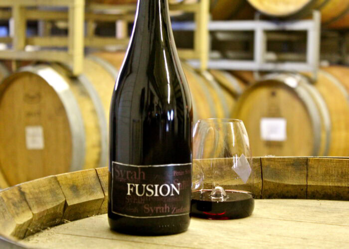 Wine bottle and glass of red wine on a barrel at Lodi Winegrape Commission.