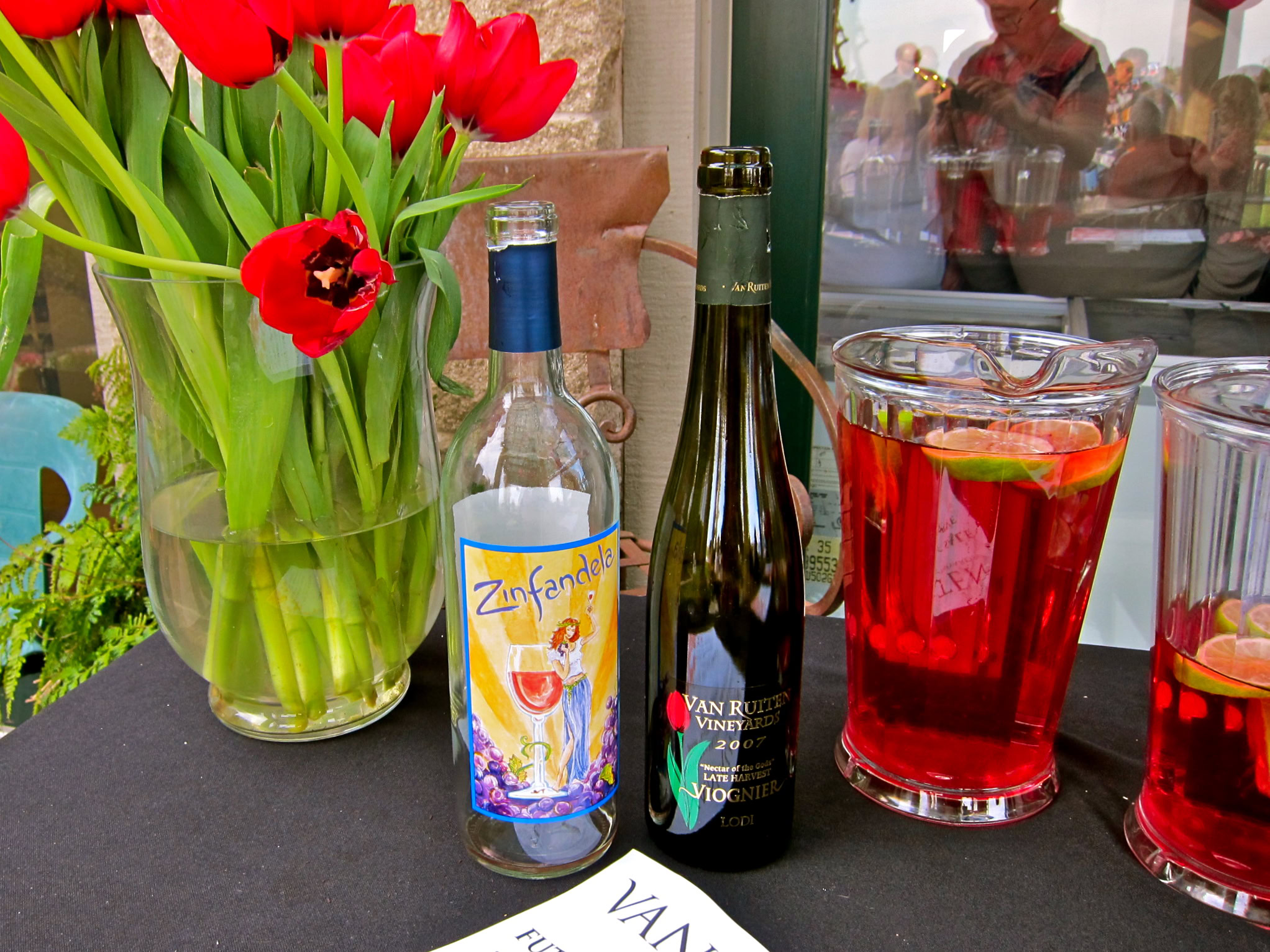 Wine bottles and glasses with red beverage and tulips at a Lodi wine event.