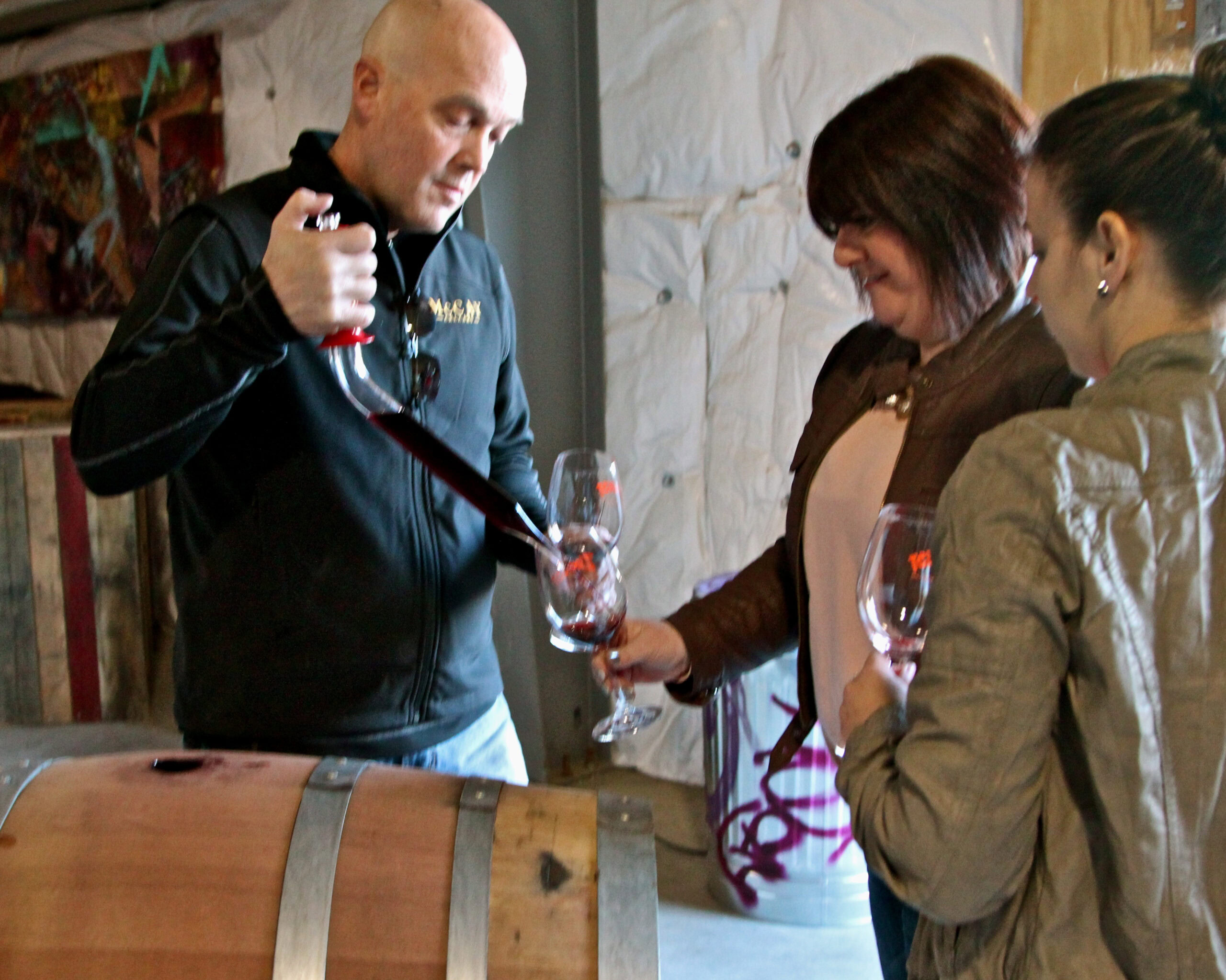 Wine expert pours wine for two women at a Lodi wine tasting event.