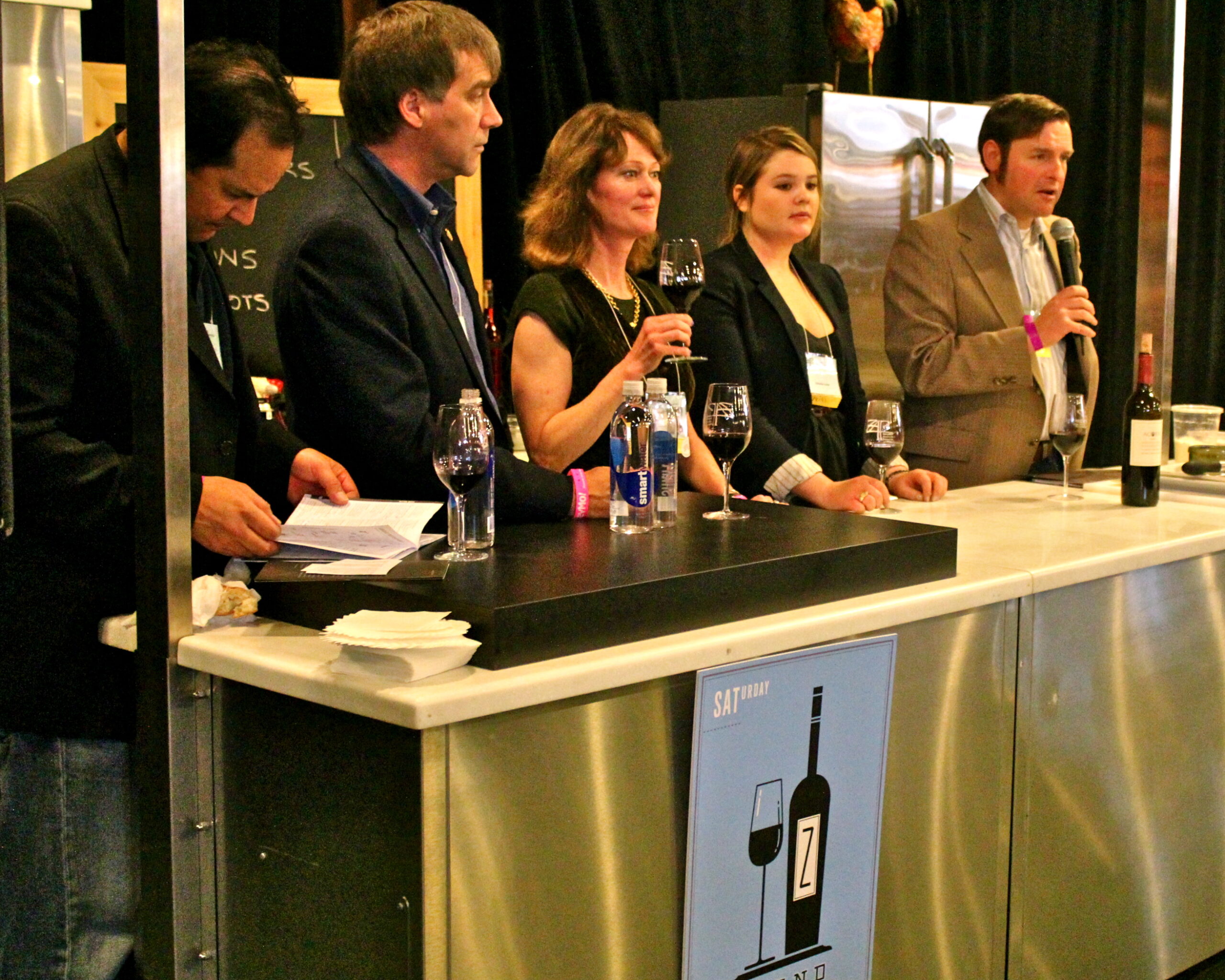 Panel of experts discussing wine at Lodi Winegrape Commission event with wine bottles and glasses.