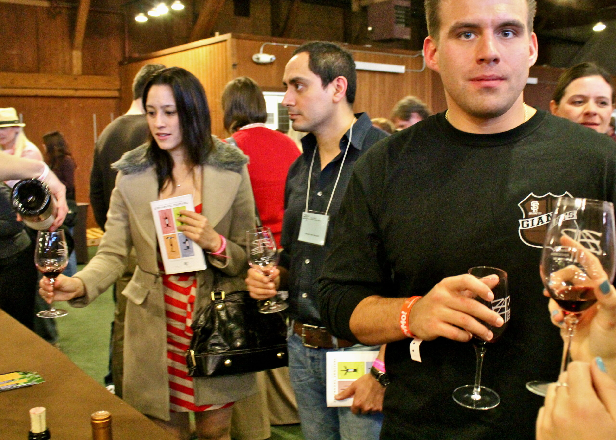 People tasting wine at a Lodi Winegrape Commission event, holding glasses and engaging in wine tasting activities.