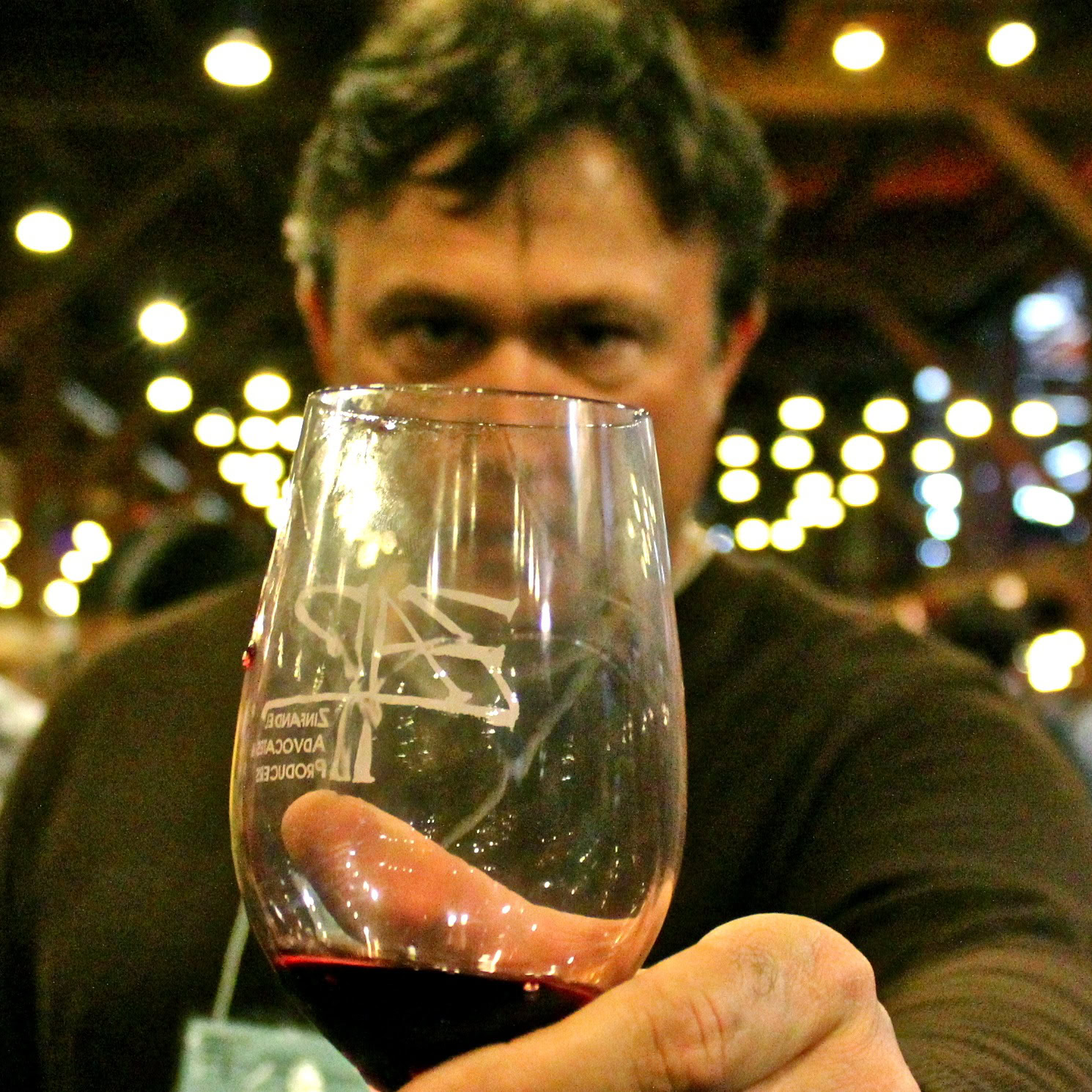 Person holding a glass of red wine at a wine tasting event in Lodi, California.