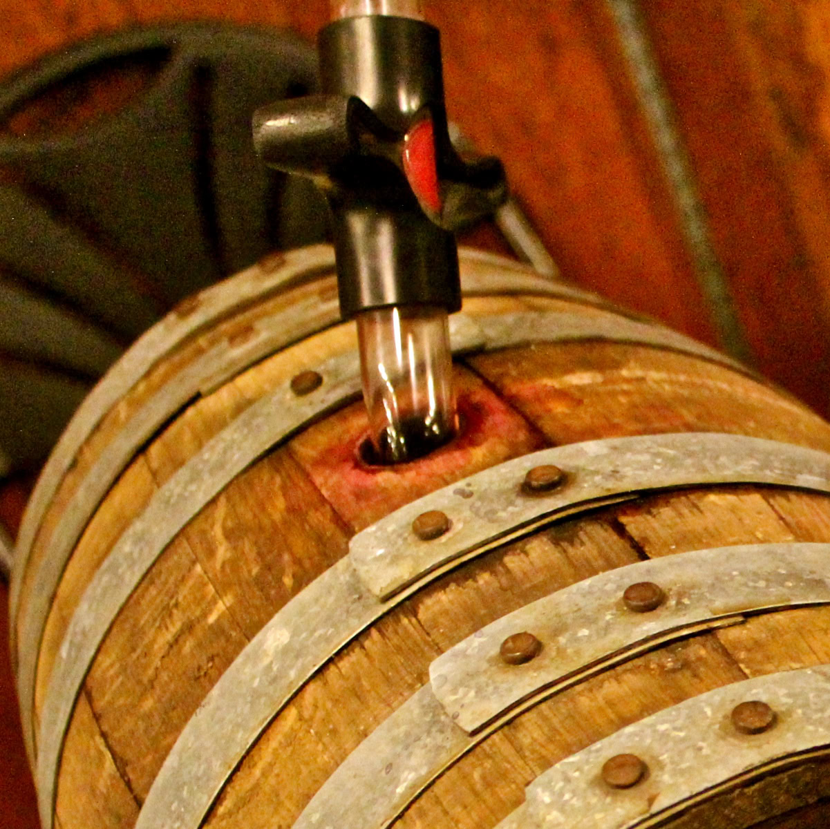 Close-up of a wine barrel with a drip irrigation system in a winery setting.