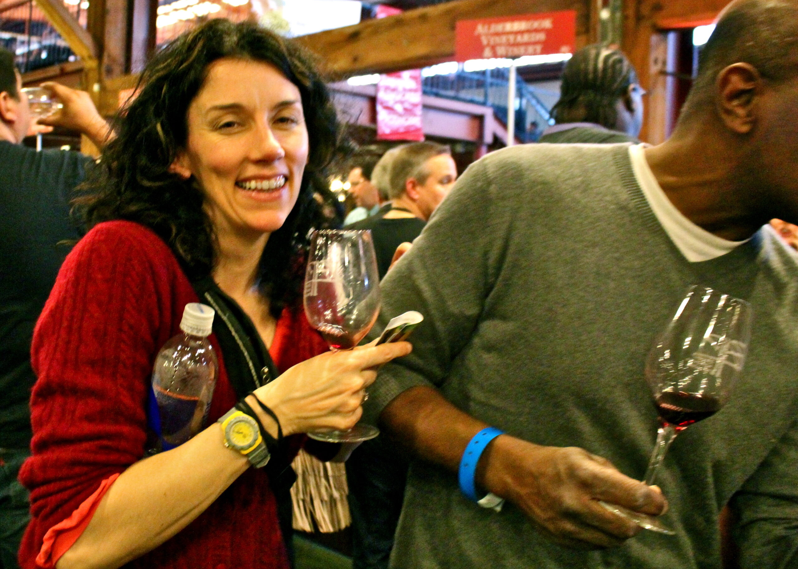 Smiling woman holding a glass of red wine at a wine tasting event in Lodi, California.