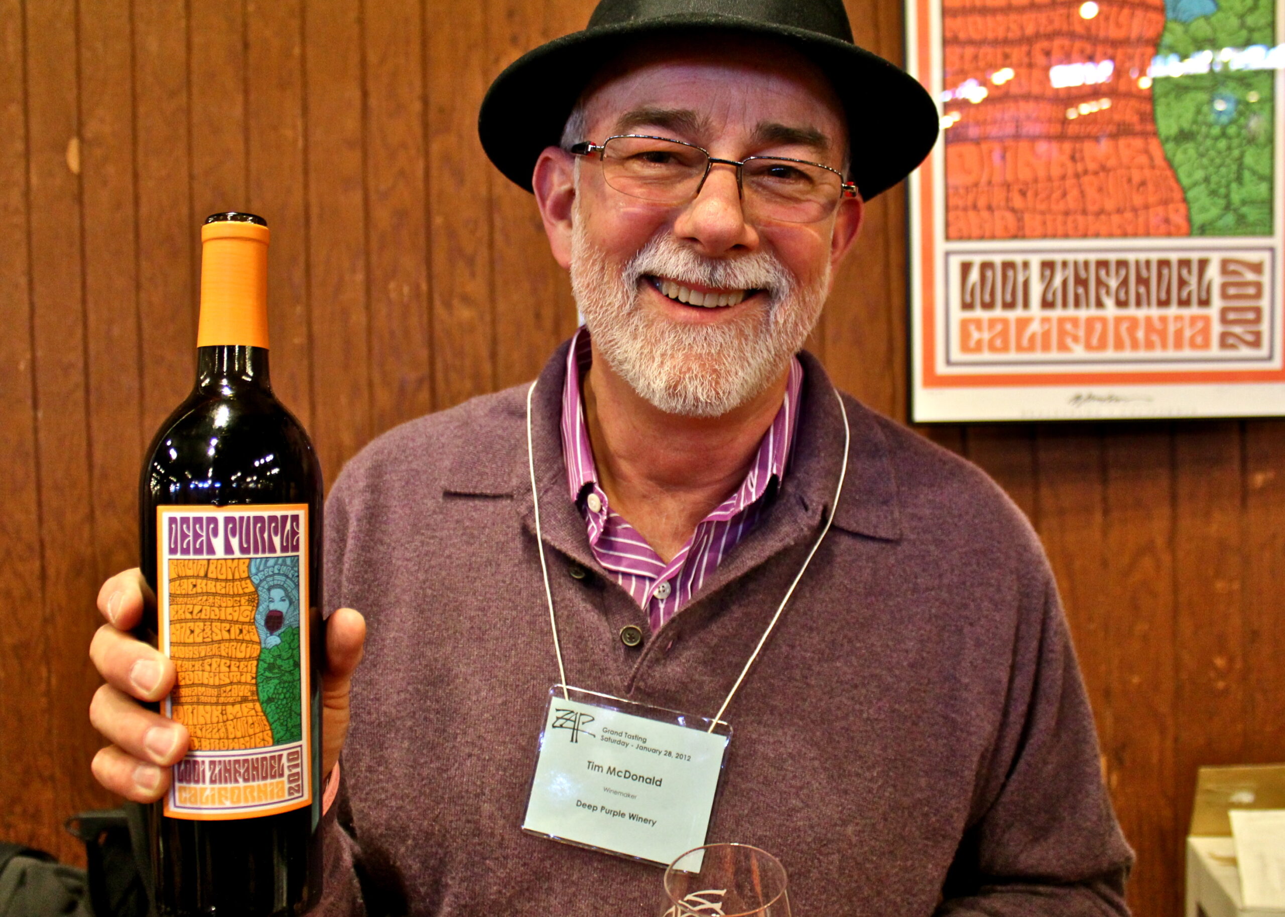 Smiling man holding a bottle of wine at a Lodi Winegrape Commission event.