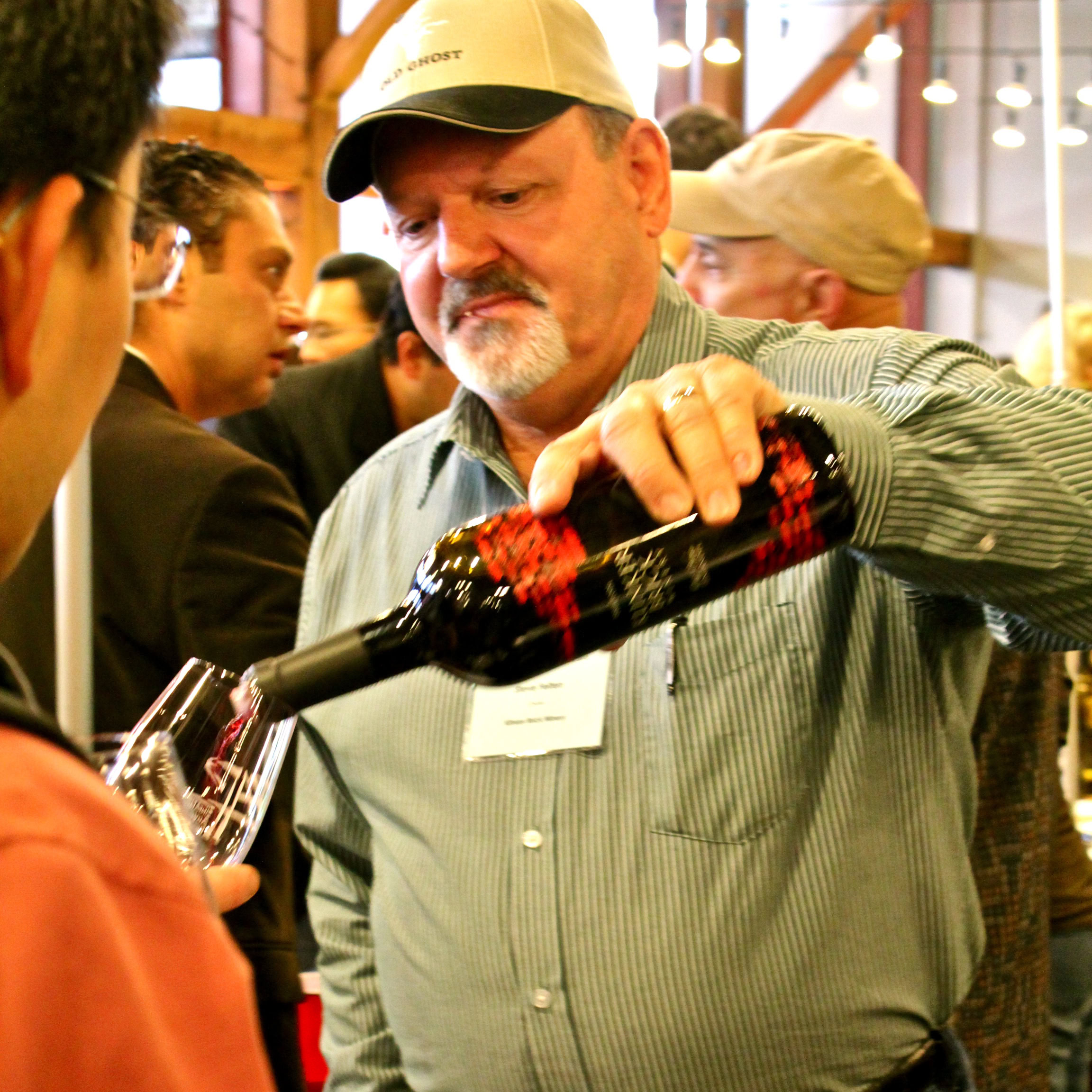 Man pouring red wine into a glass at a Lodi wine event, showcasing local wine culture.