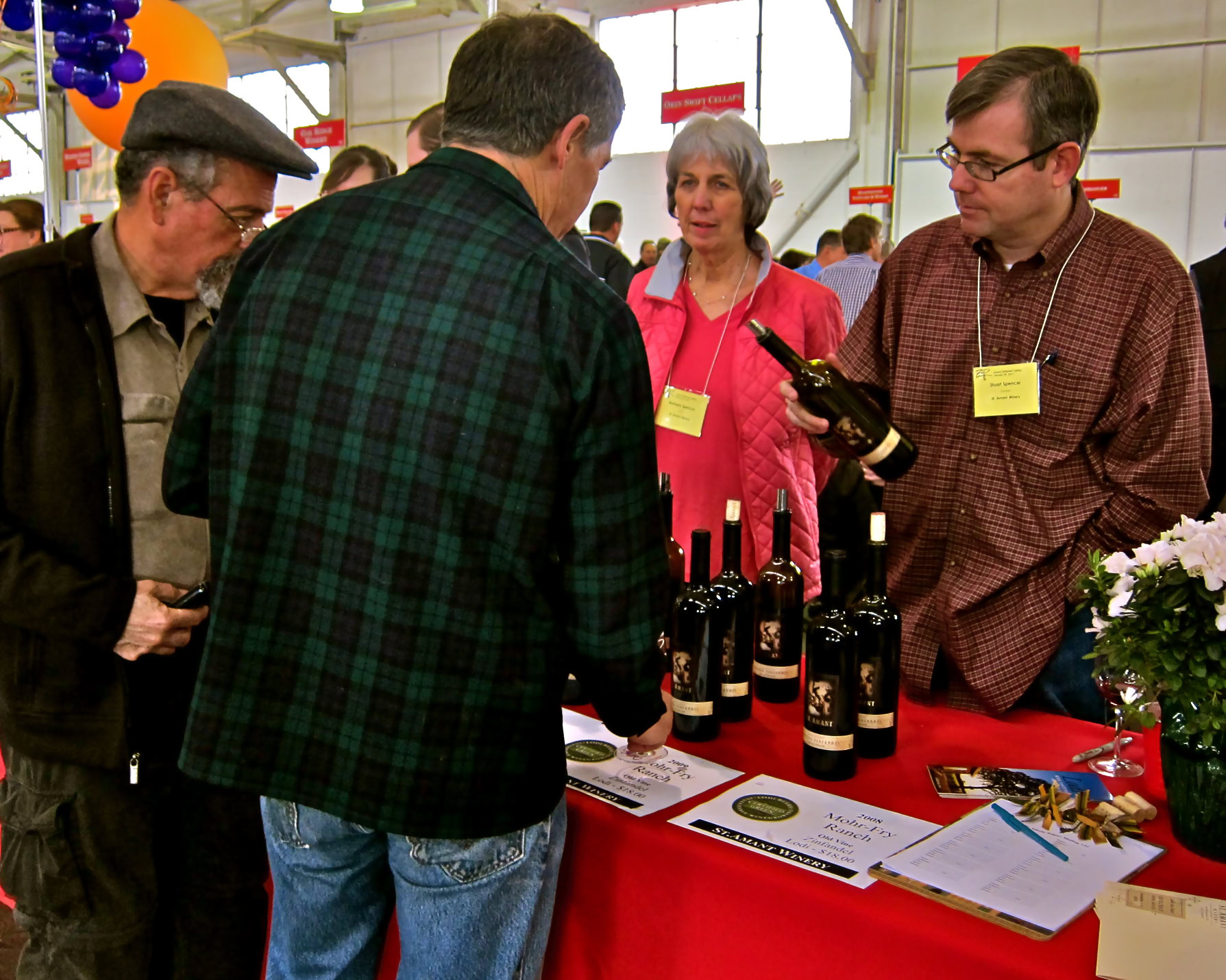 People tasting and discussing wines at a Lodi Winegrape Commission event in a busy indoor setting.