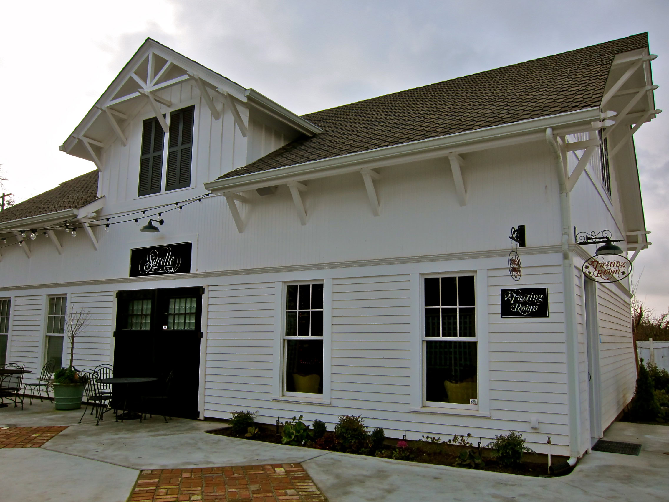 White winery building with black signage and outdoor seating, located in Lodi, California.