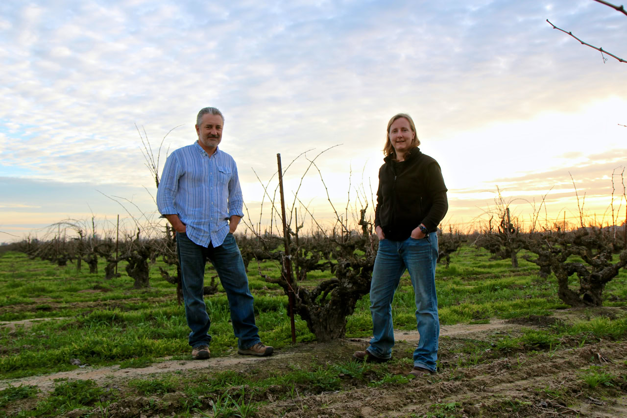 Two people standing in a vineyard at sunset, showcasing Lodi winegrapes and grapevines.