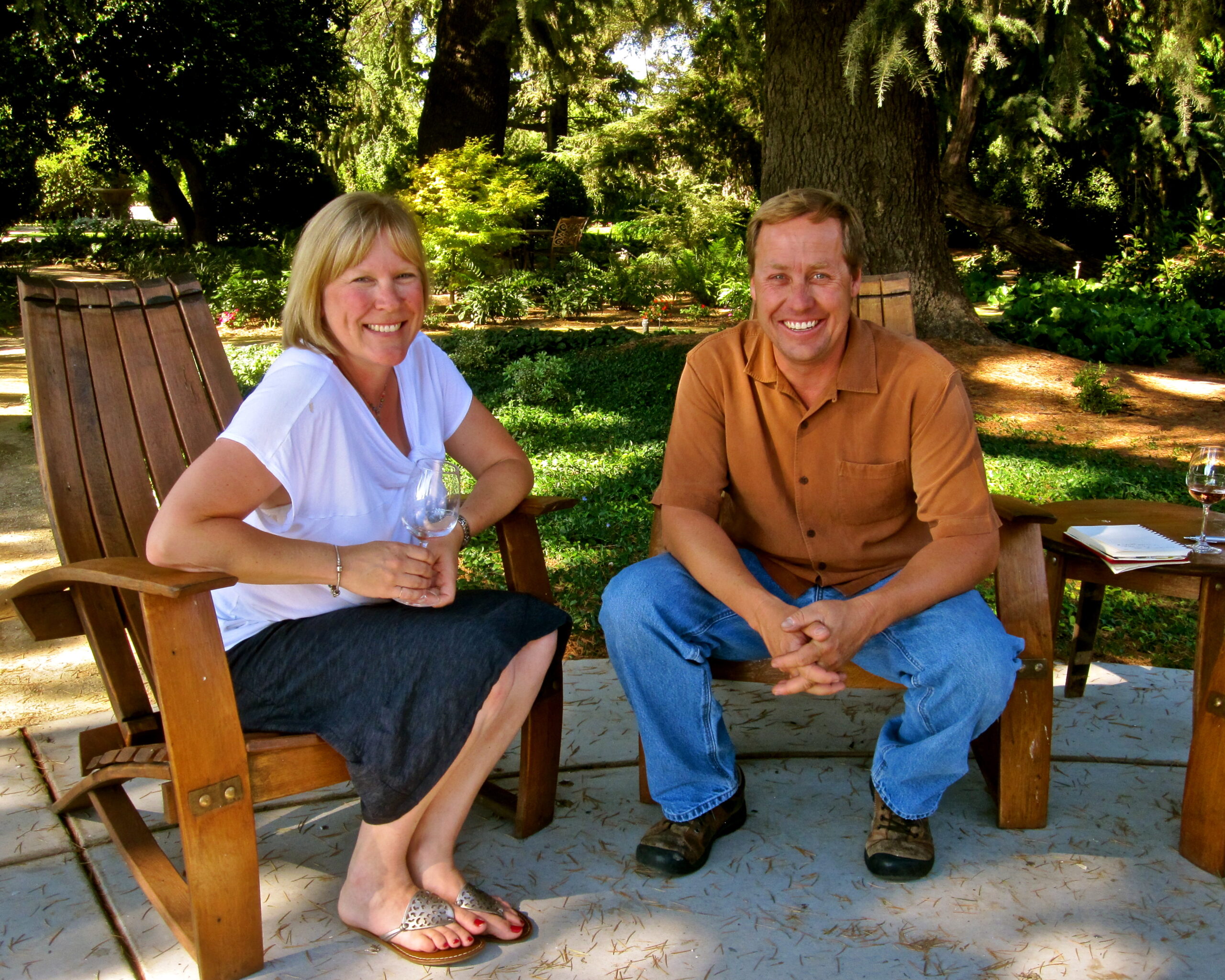 Two people enjoying wine outdoors at a Lodi Winegrape Commission event in a lush garden setting.
