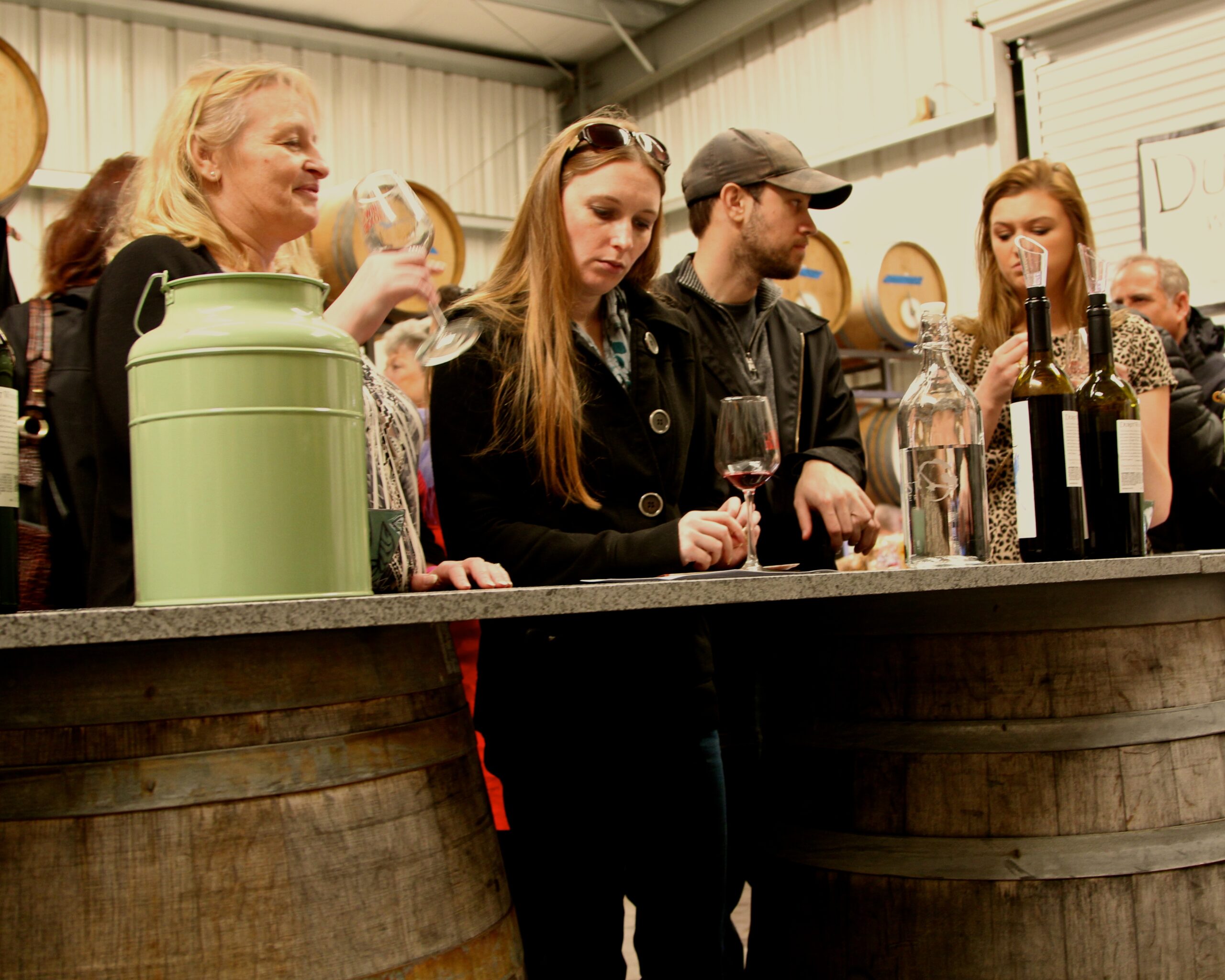 People tasting wine at a Lodi Winegrape Commission event in a winery setting.