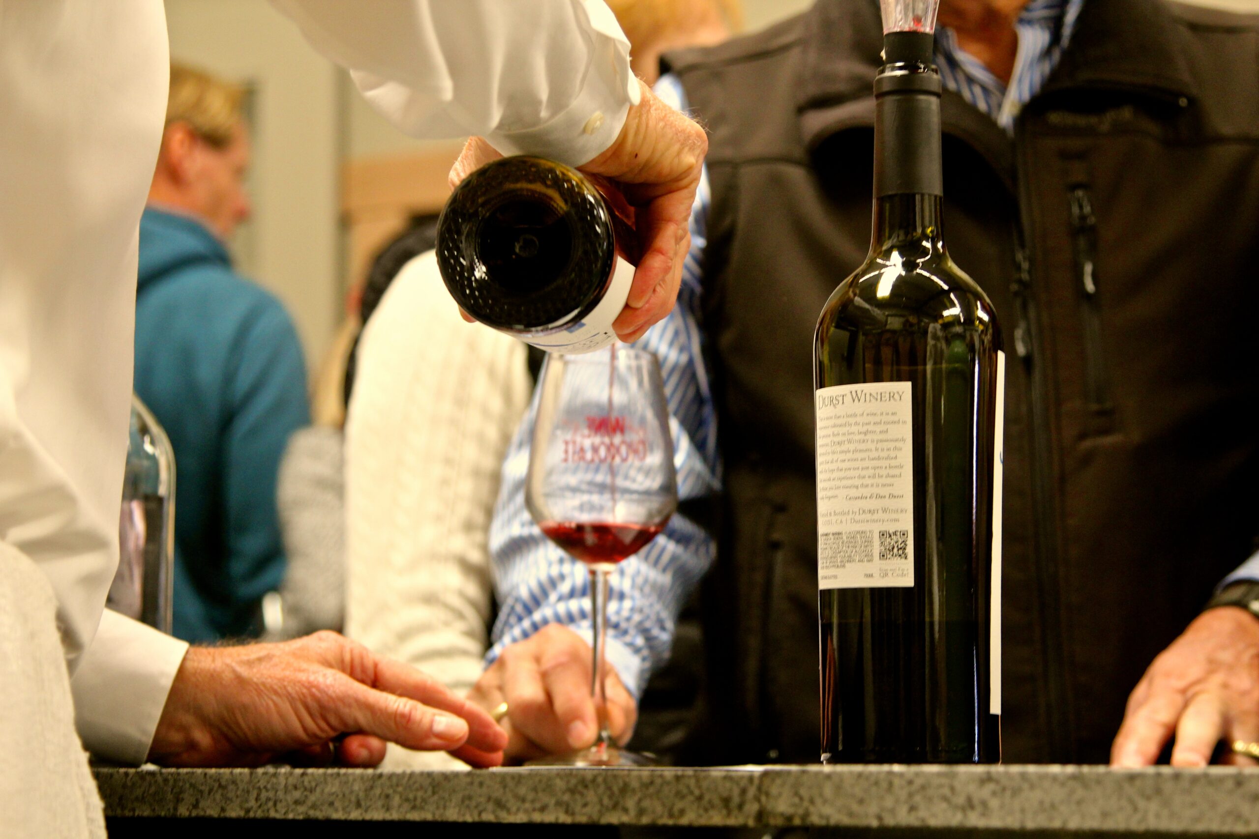 Person pouring red wine into a glass at a wine tasting event in Lodi, California.