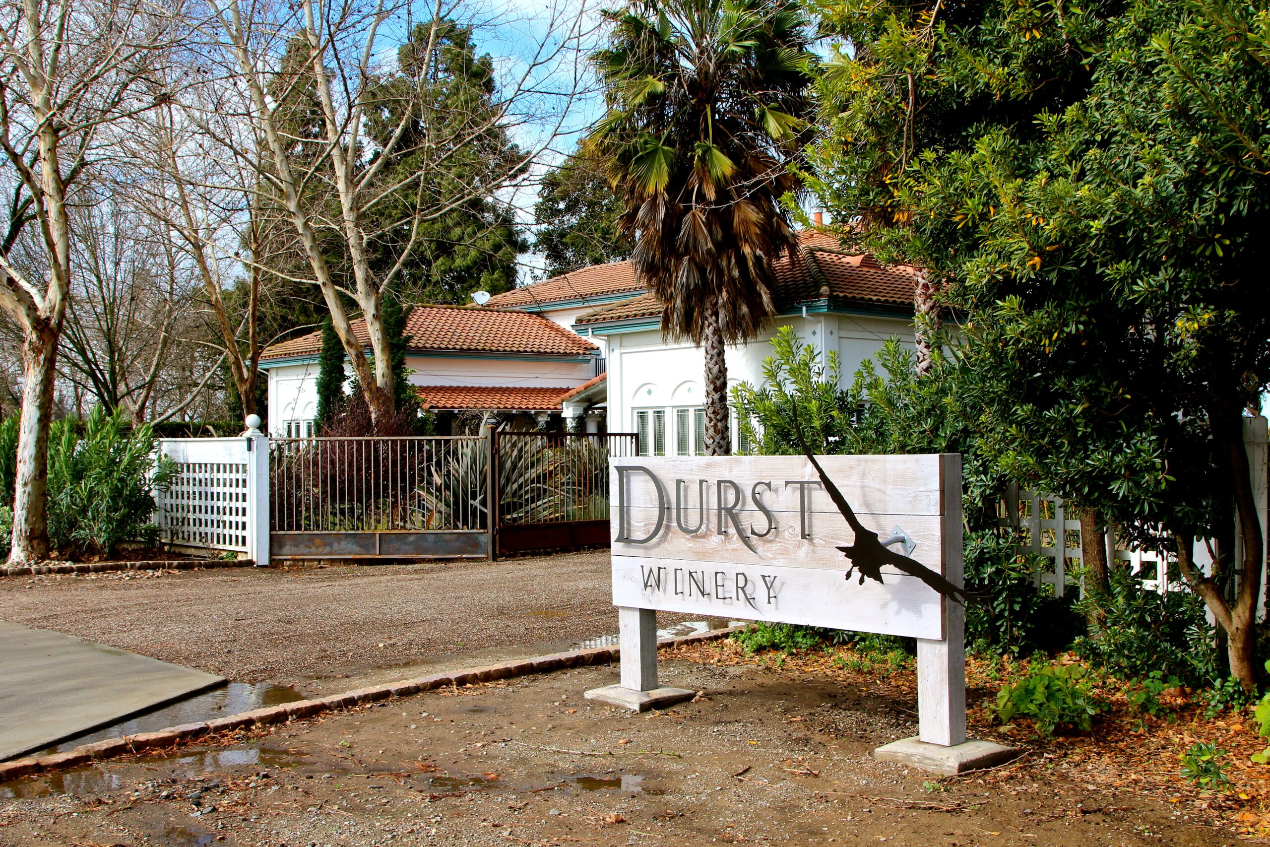 Durst Winery sign with a bird silhouette, surrounded by trees and a house in Lodi, California.