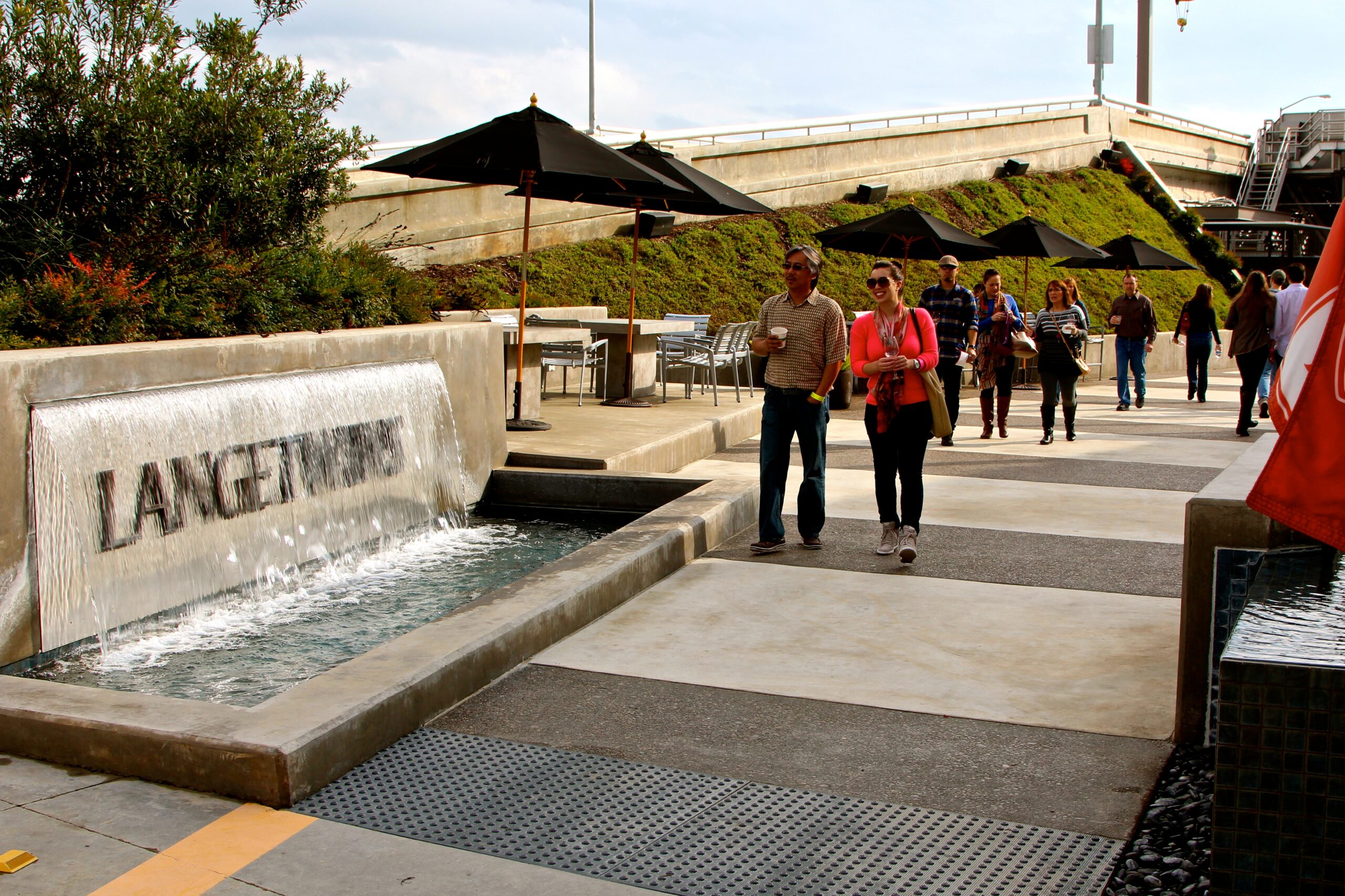 People walking near a water feature with umbrellas at Lodi Winegrape Commission.