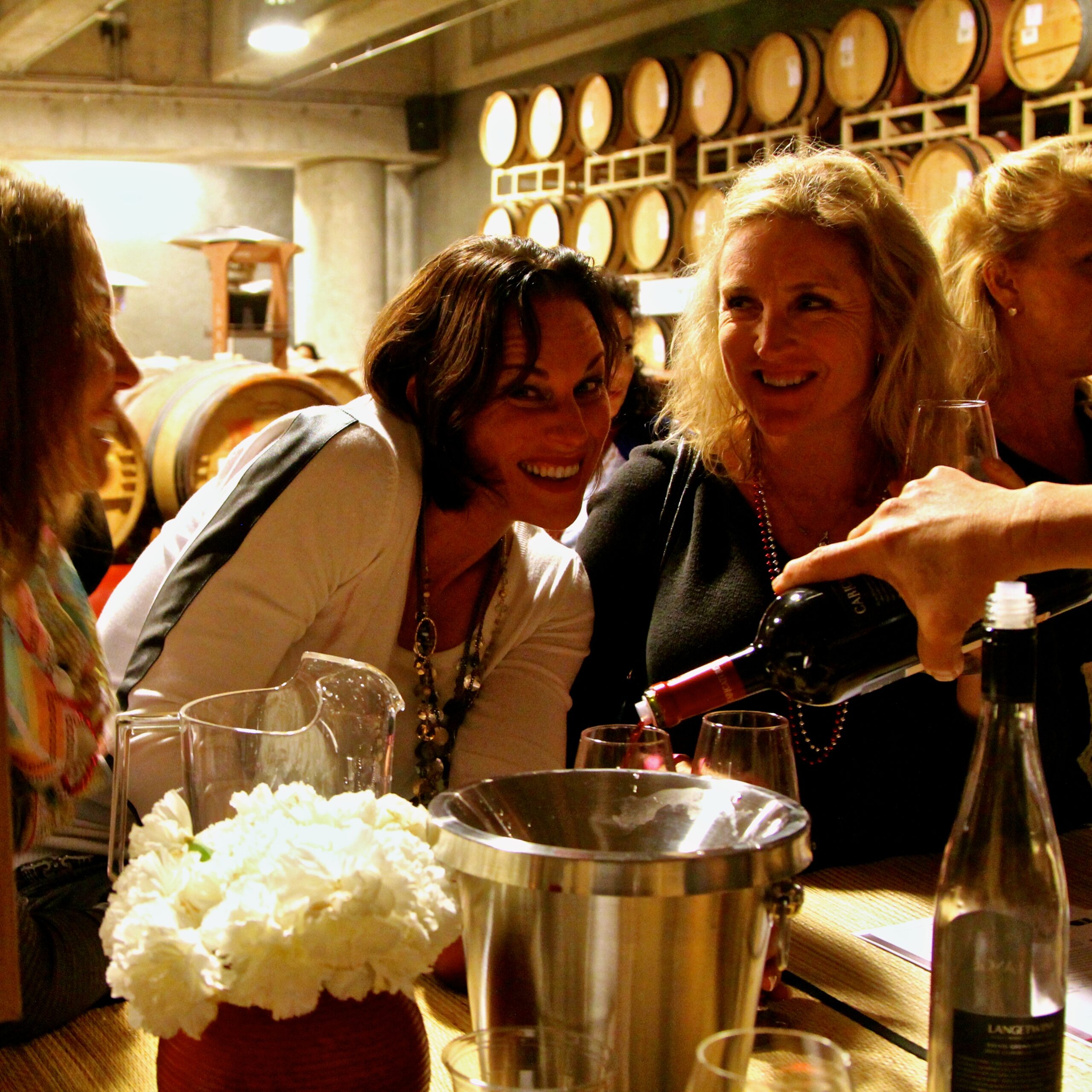 People enjoying wine tasting at Lodi Winegrape Commission event in a winery setting.