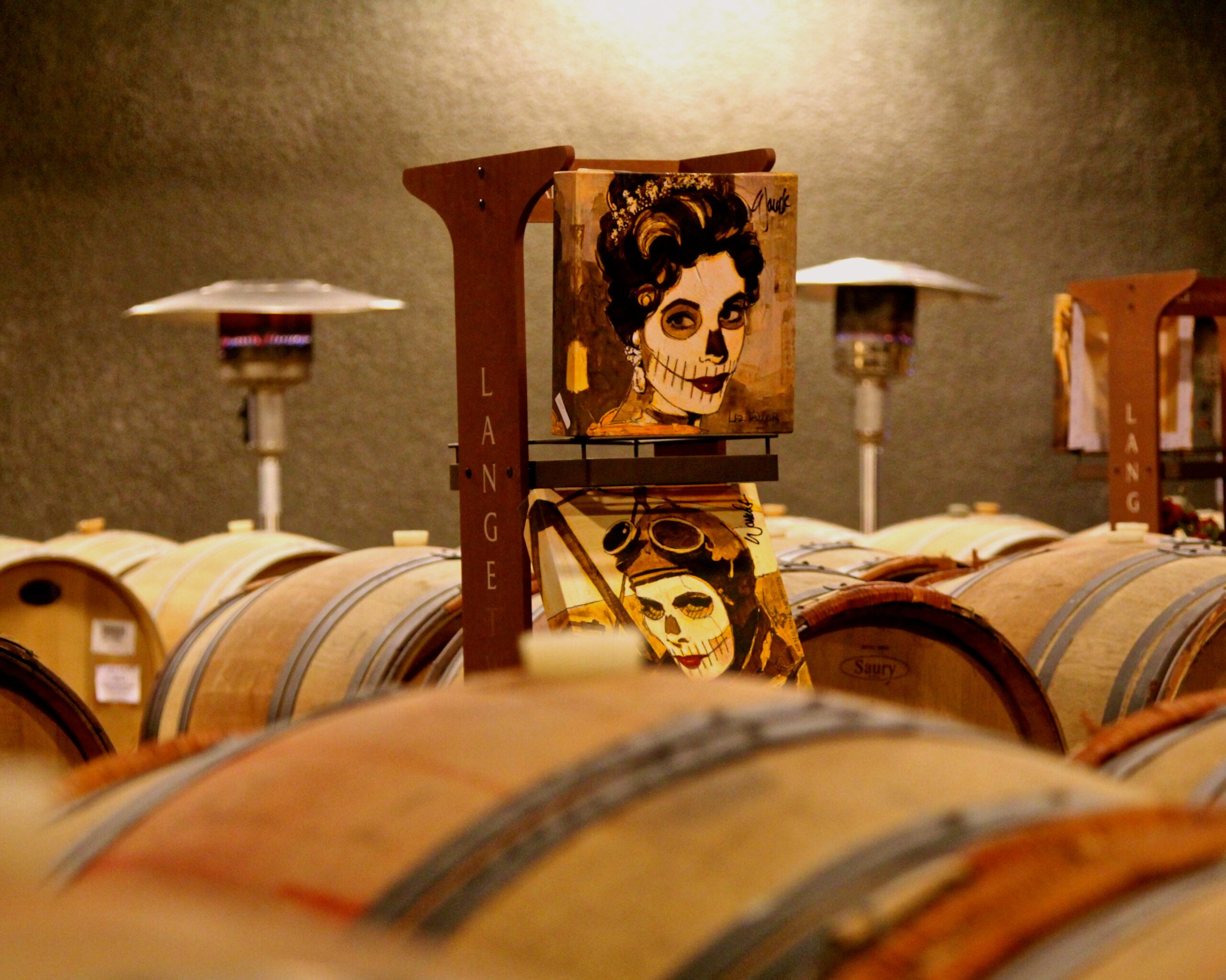 Wine barrels in a cellar with artwork promoting Lodi Winegrape Commission.