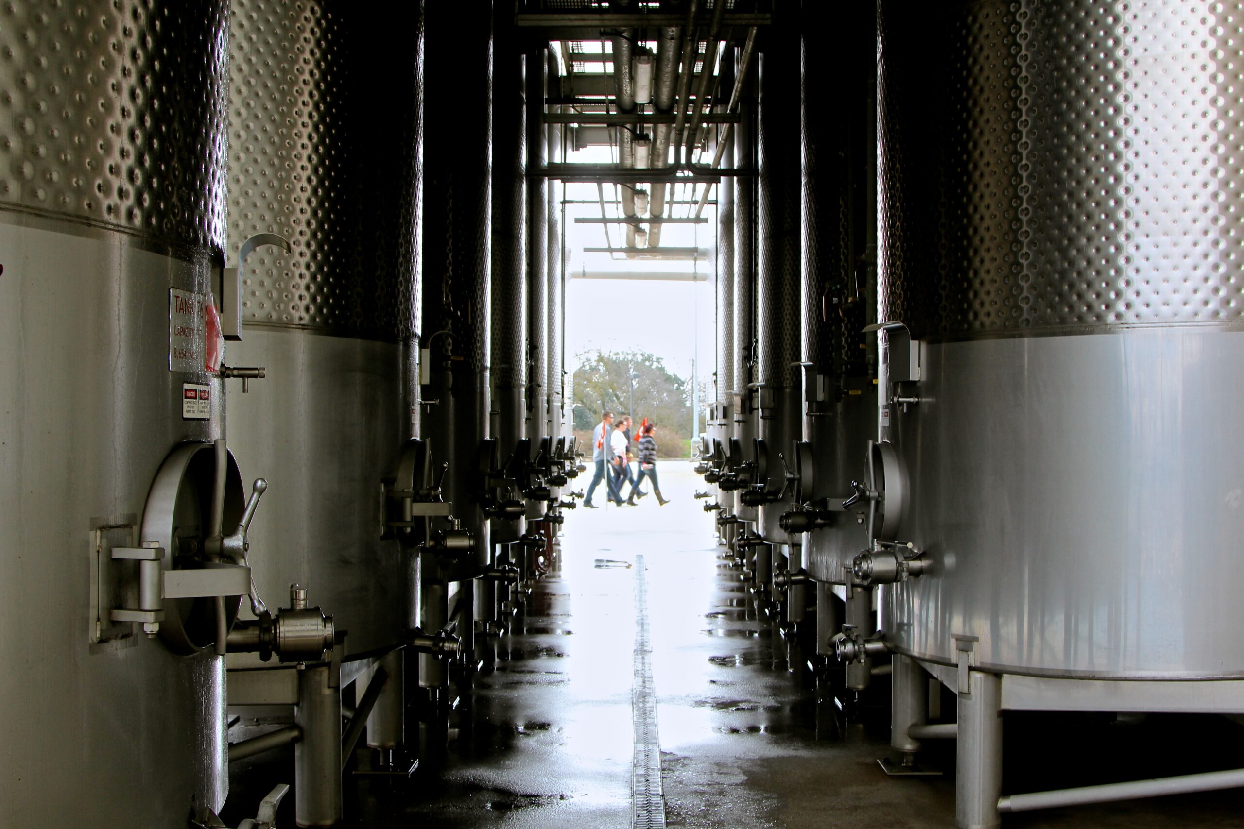 Winery tanks at Lodi Winegrape Commission with workers in the background.