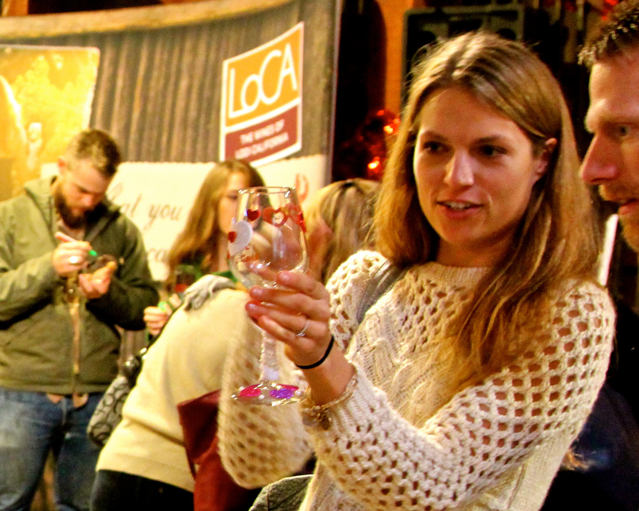 Woman holding a wine glass at a Lodi Winegrape Commission event in a lively setting.
