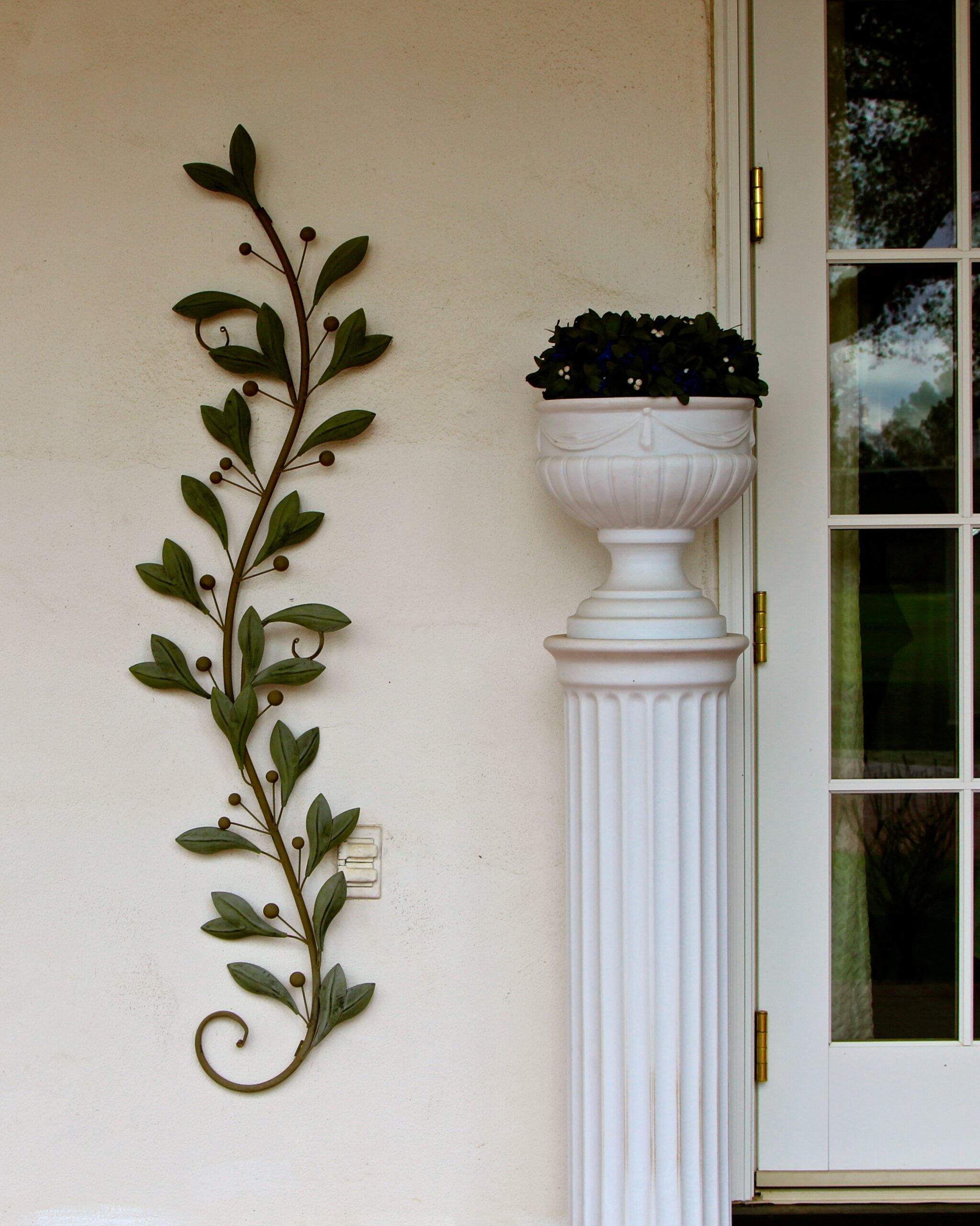 Decorative plant and classical column outside a house, enhancing curb appeal and aesthetic value.