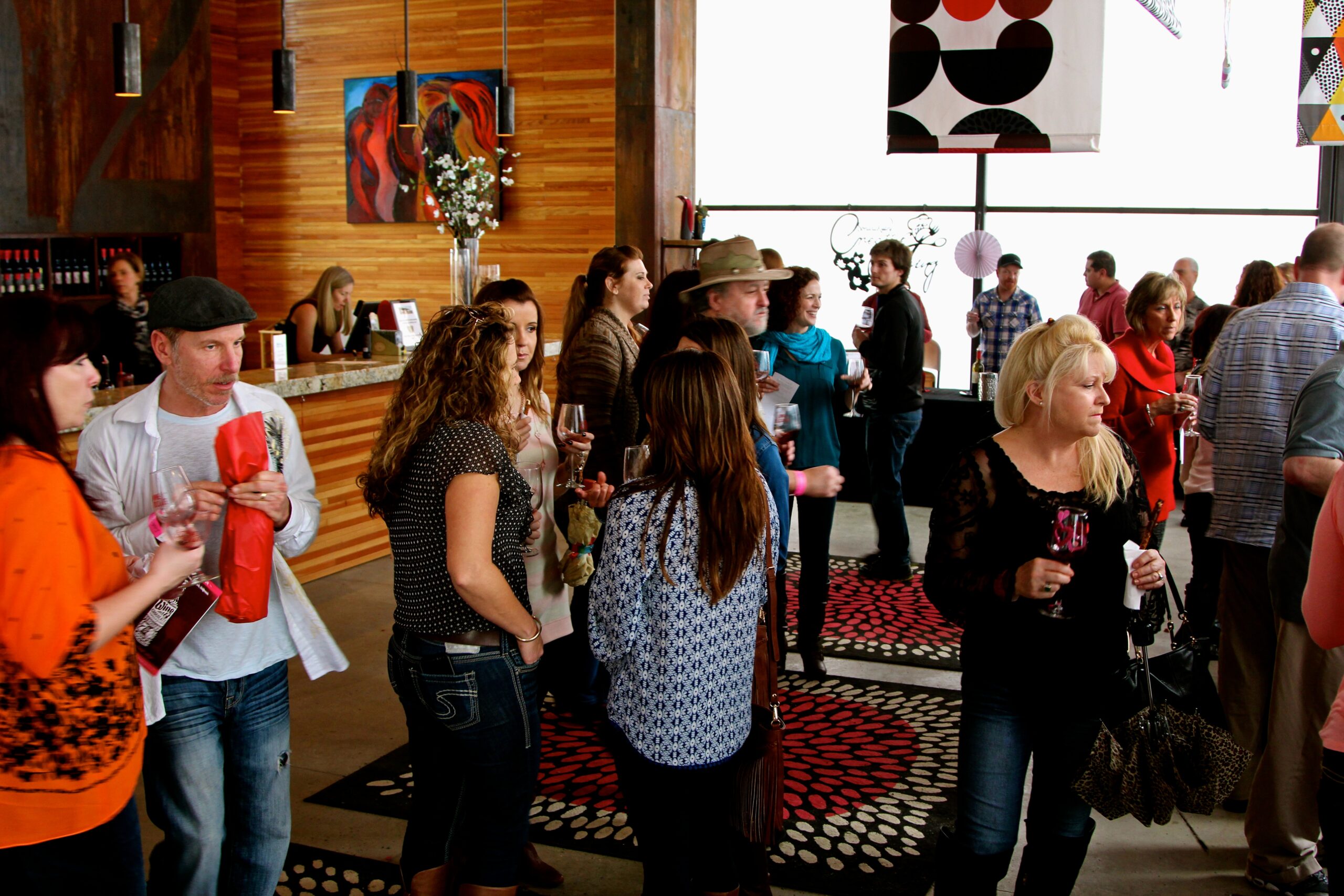 People attending a Lodi Winegrape Commission event in a modern venue with artwork and a patterned carpet.