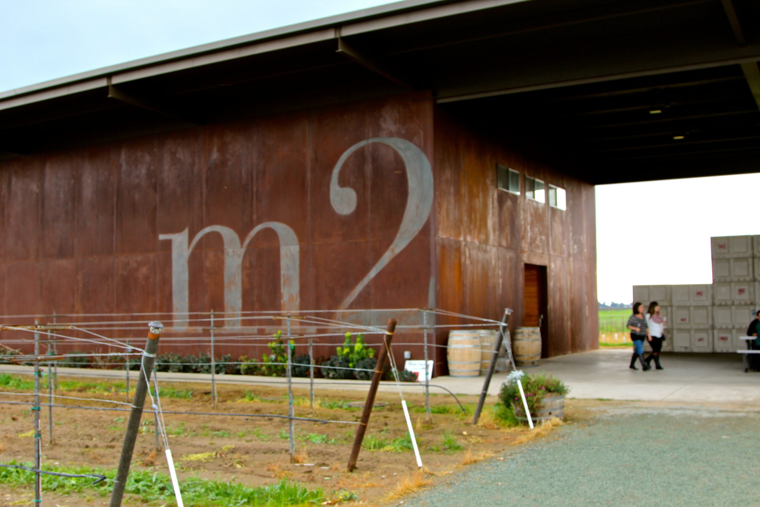 Modern winegrape research facility with rust-colored exterior and vineyard in foreground.
