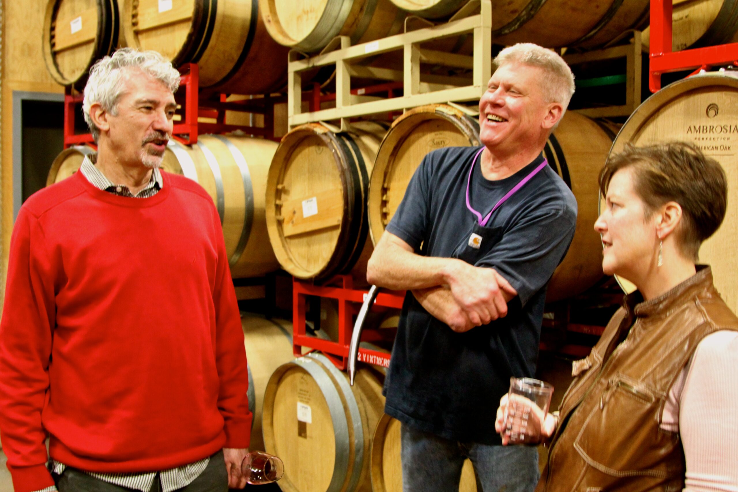 People networking at a wine barrel storage with smiles and conversation, showcasing Lodi wine industry collaboration.