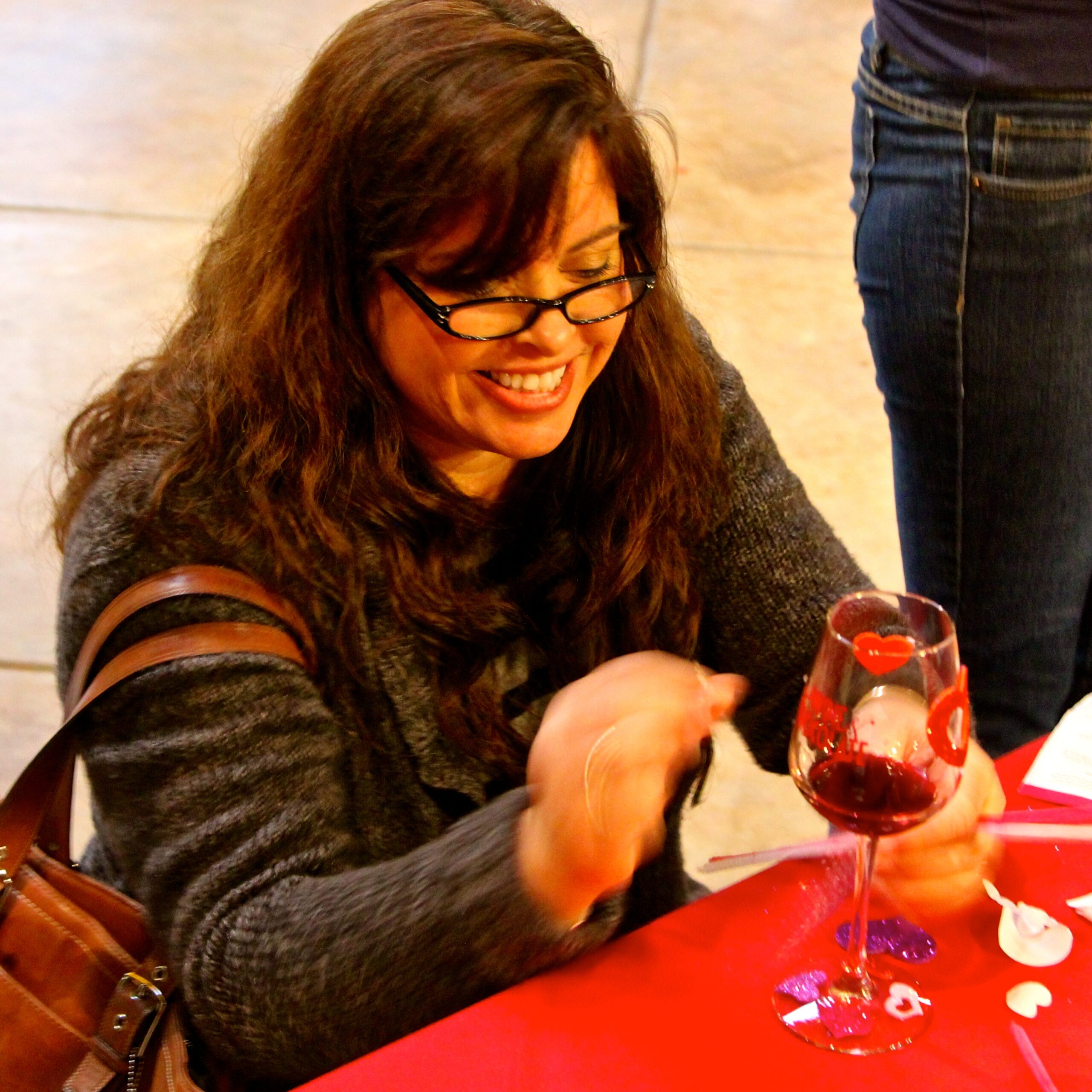 Woman enjoying wine tasting at Lodi Winegrape Commission event with glass of red wine.