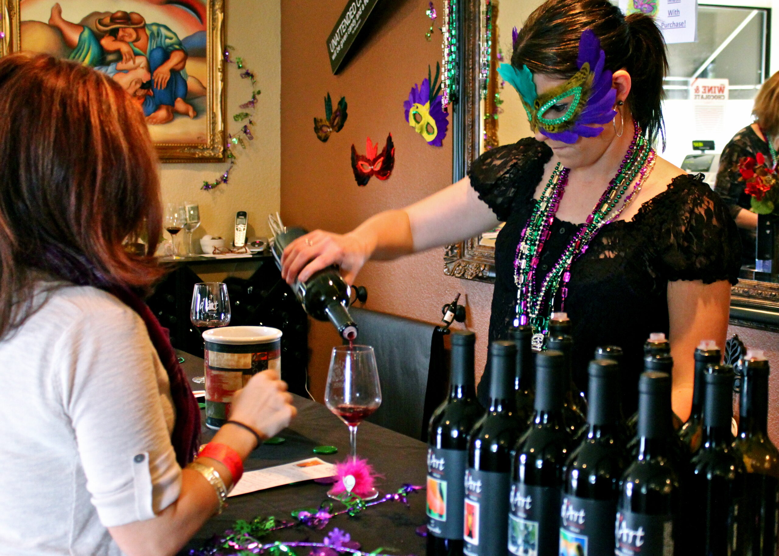 Woman in Mardi Gras mask pouring wine at Lodi Winegrape Commission event.