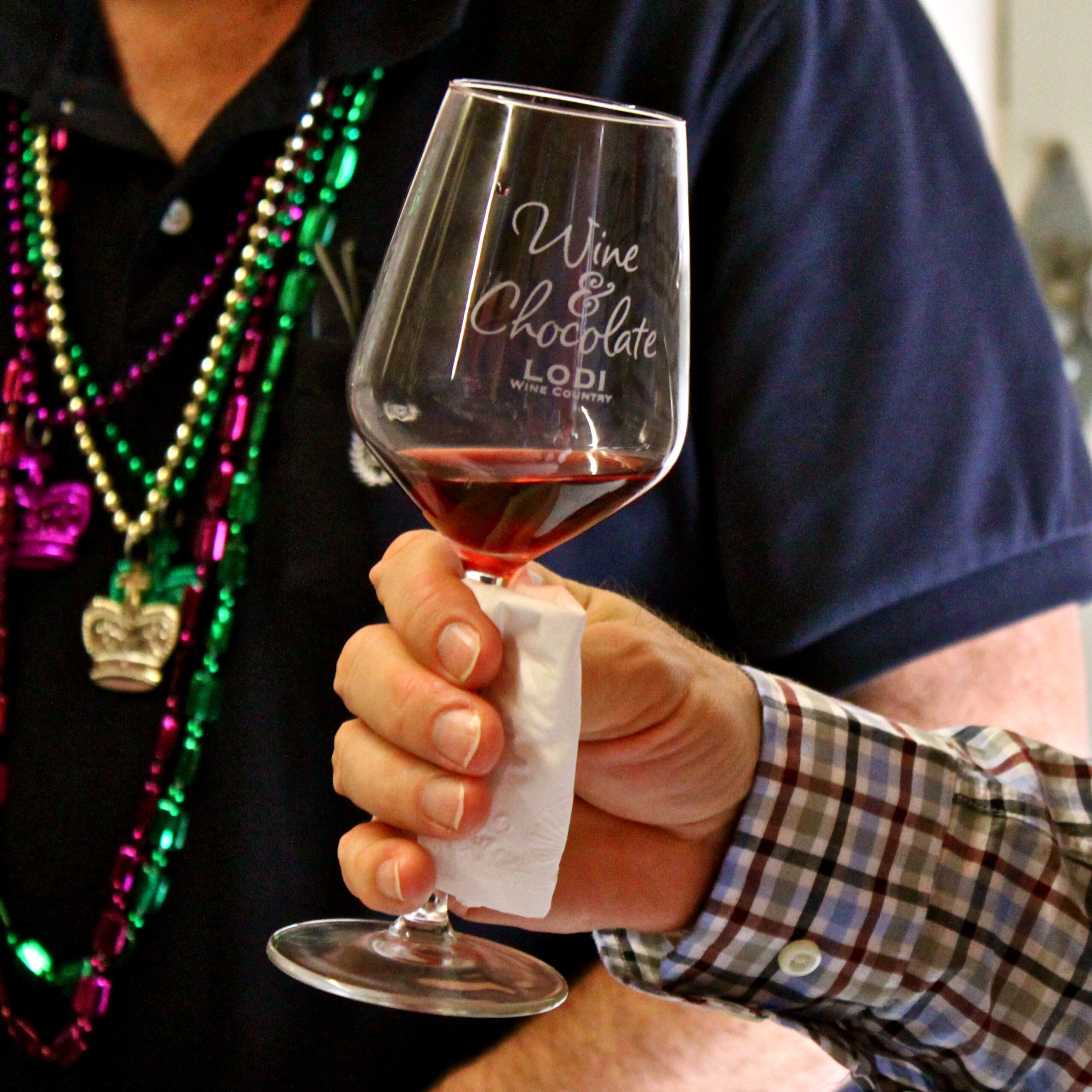 Close-up of a hand holding a glass of red wine at a wine and chocolate event in Lodi, California.
