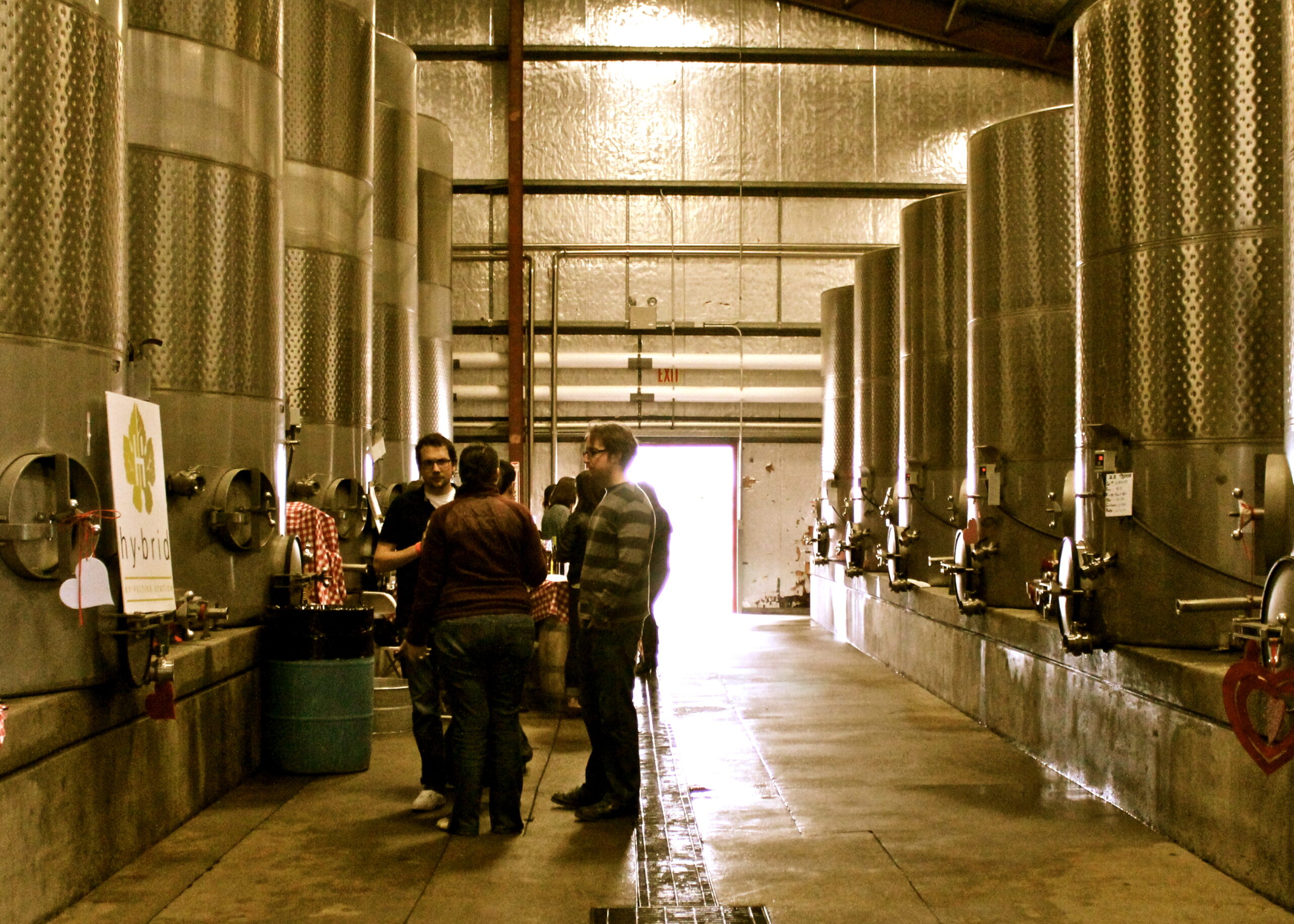 Group of people touring a winery with large fermentation tanks in Lodi, California.