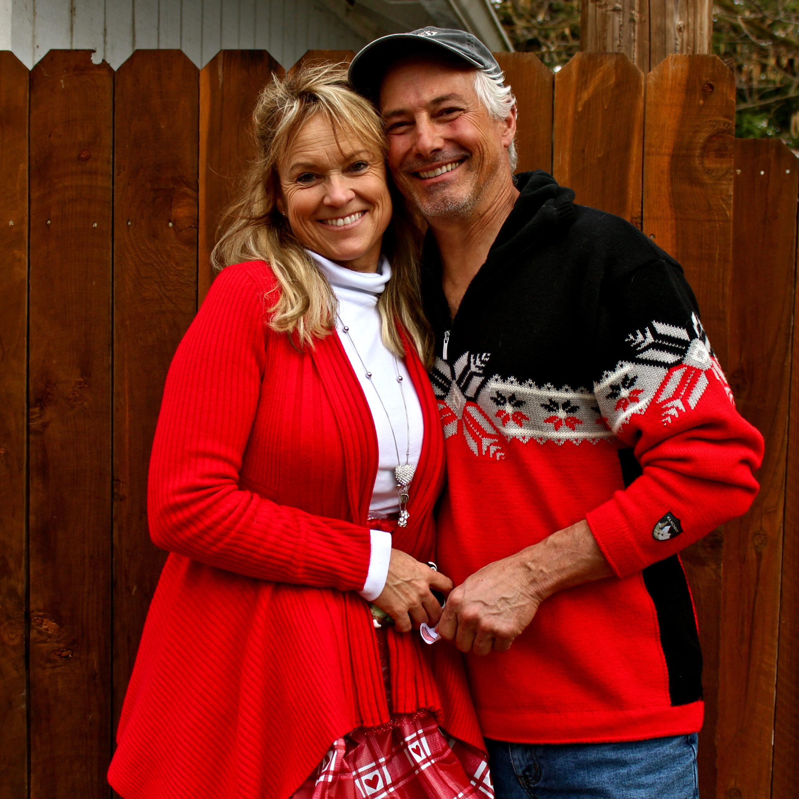 Smiling couple at Lodi Winegrape Commission event in front of a wooden fence.