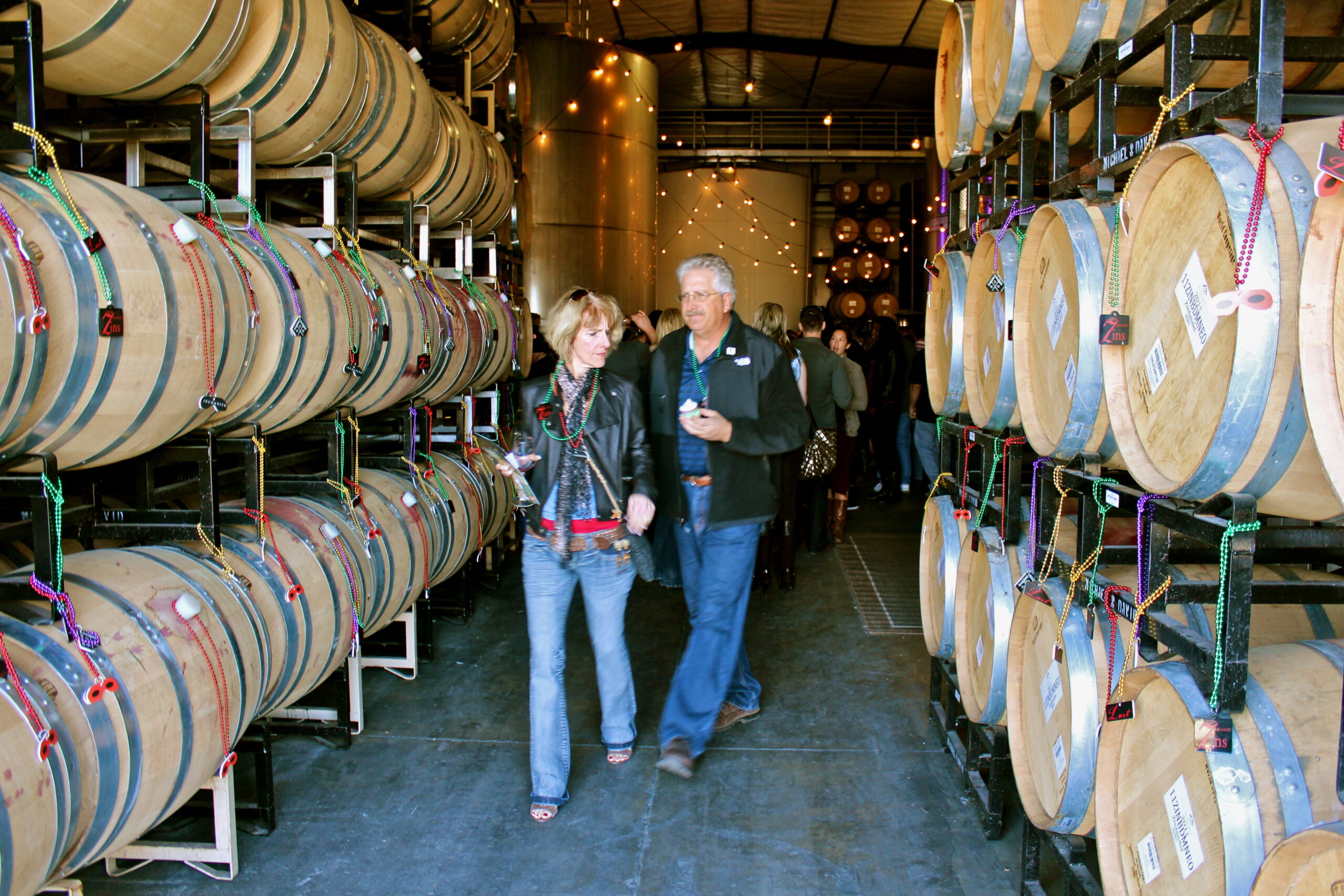 Visitors exploring wine barrels at a winery, showcasing Lodi Winegrape Commission's wine production process.