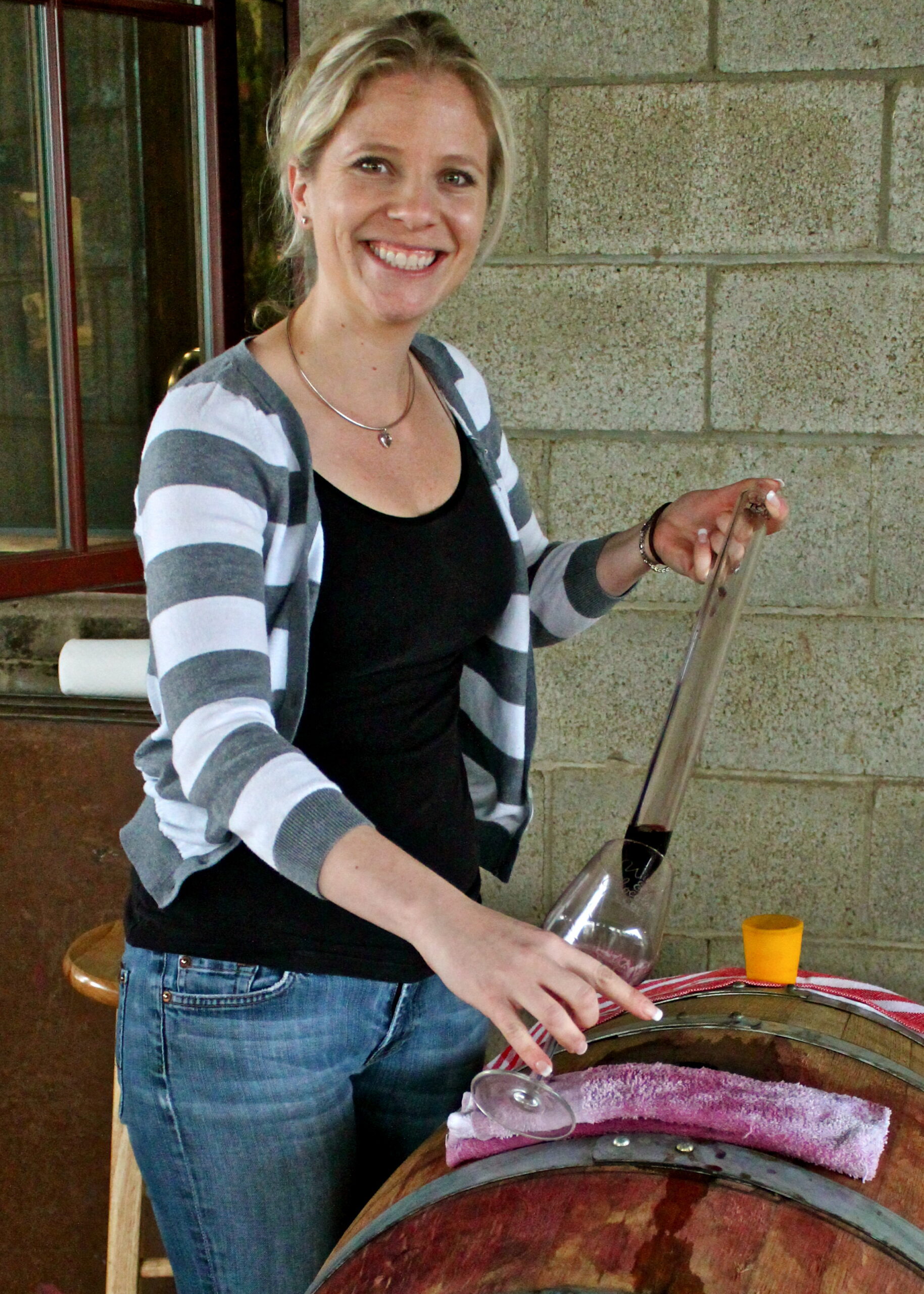 Smiling woman pouring wine at Lodi Winegrape Commission event, showcasing local wine production.
