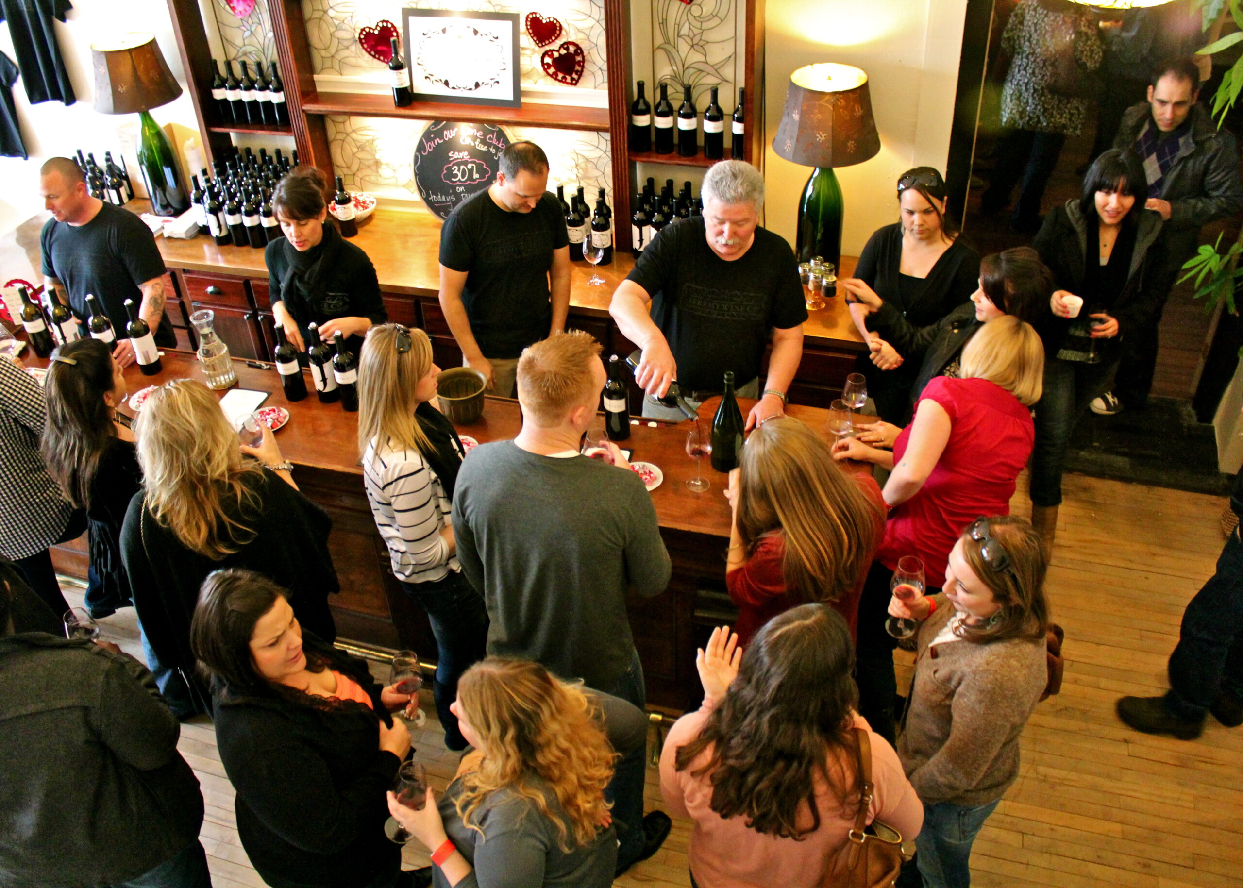 People enjoying wine tasting at Lodi Winegrape Commission event in a cozy winery setting.