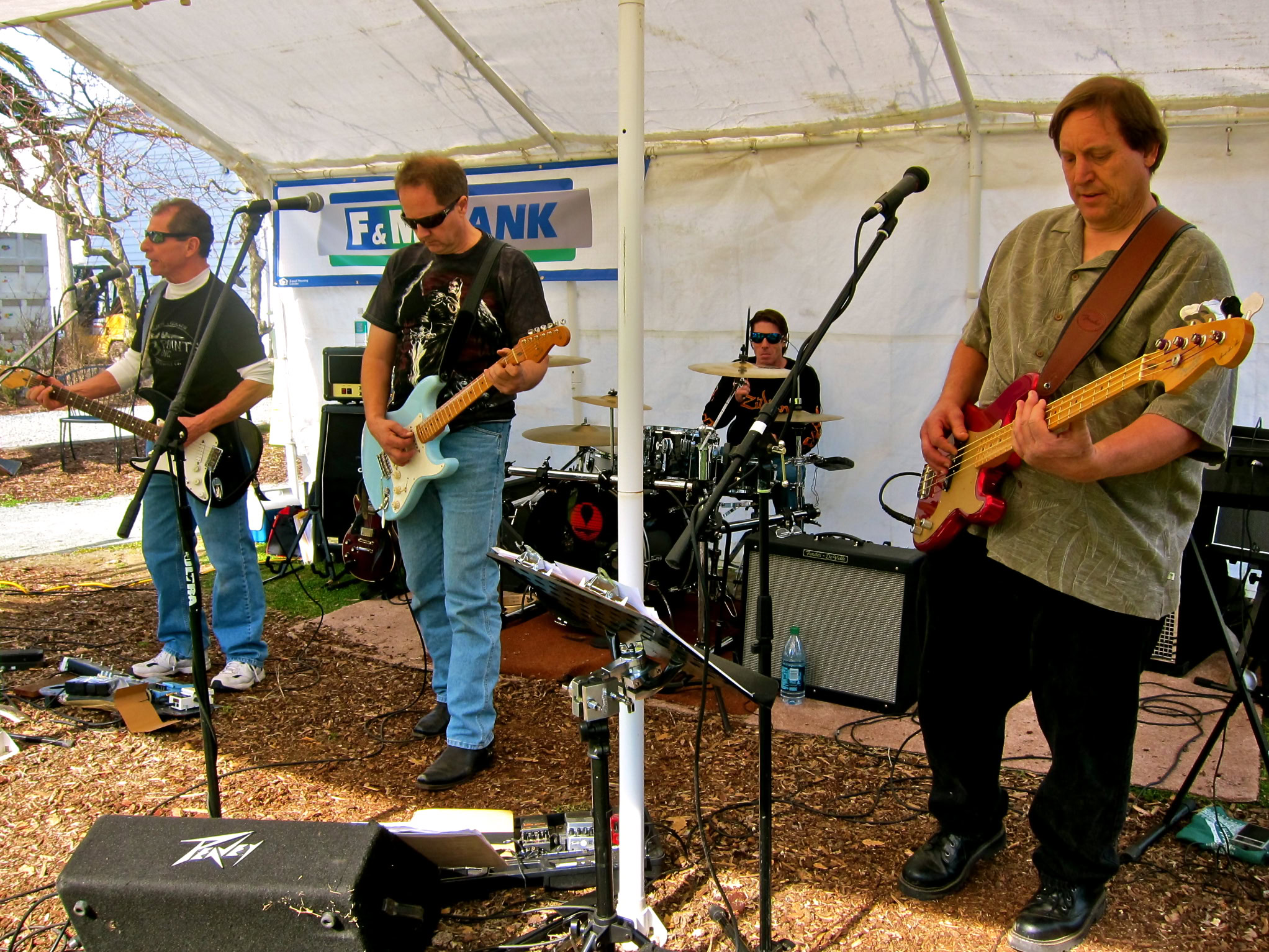 Live band performing outdoors at a Lodi Winegrape Commission event with instruments and sound equipment.