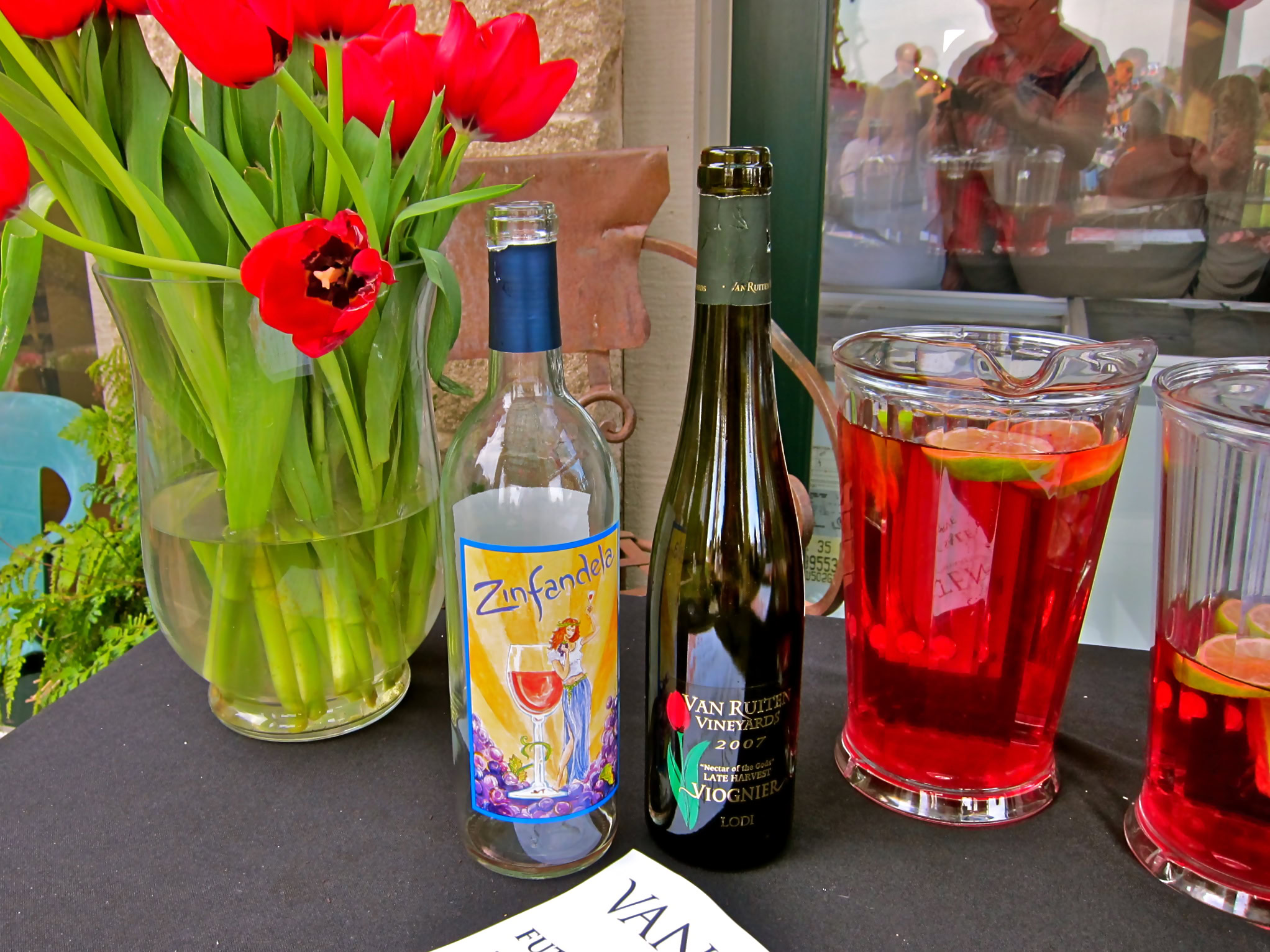 Wine bottles and glasses with red beverage and tulips at a Lodi wine event.