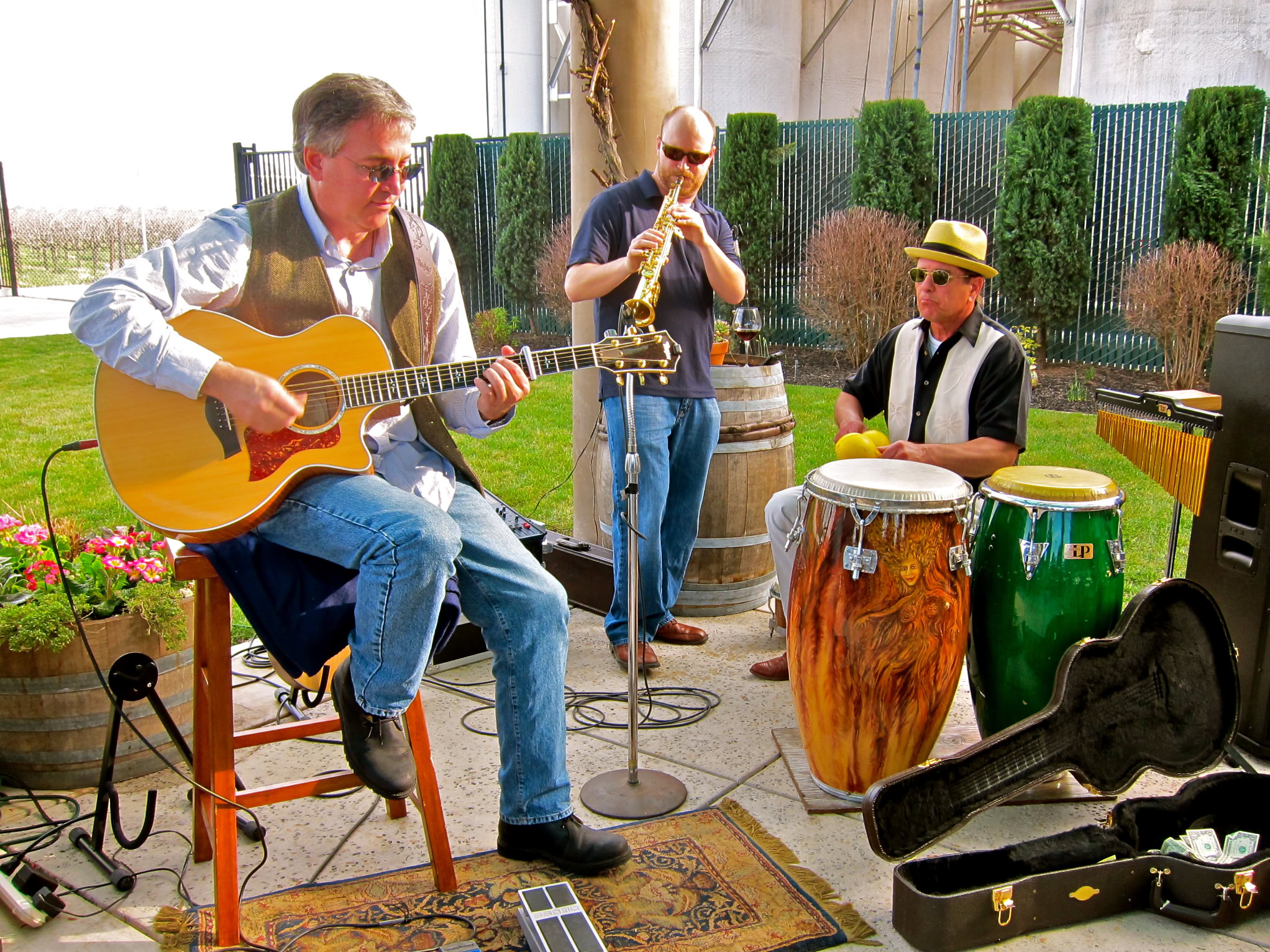 Musicians playing guitar, saxophone, and conga drums at a Lodi wine event.