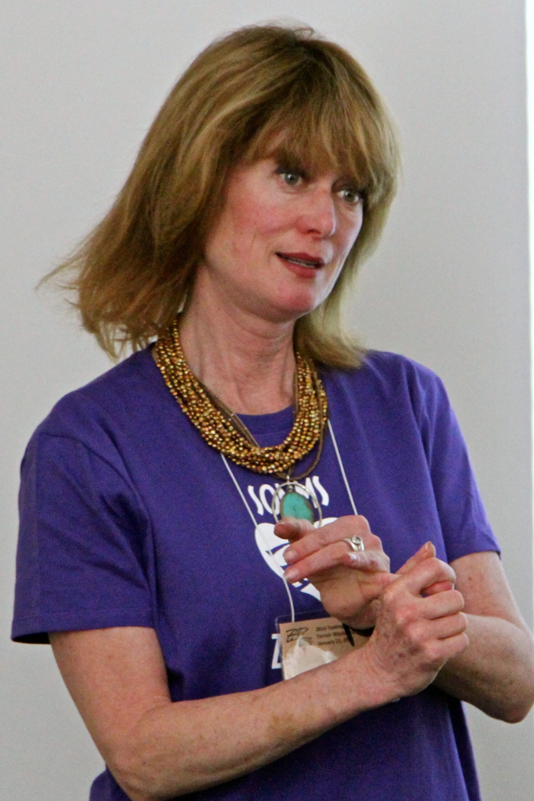Woman speaking at Lodi Winegrape Commission event, wearing a purple shirt and gold necklace.