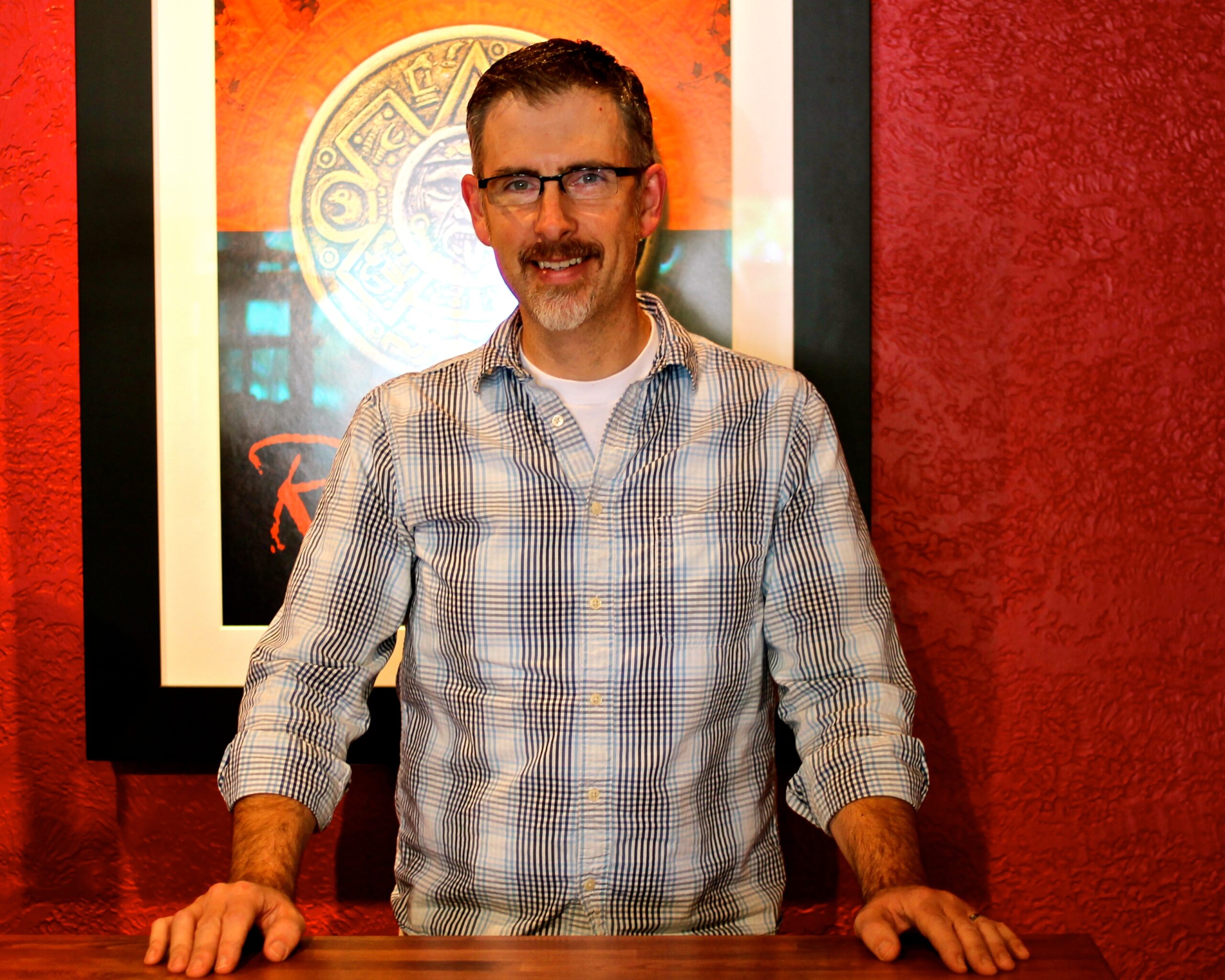 Man smiling at a wine event, standing in front of a Lodi Winegrape Commission poster.