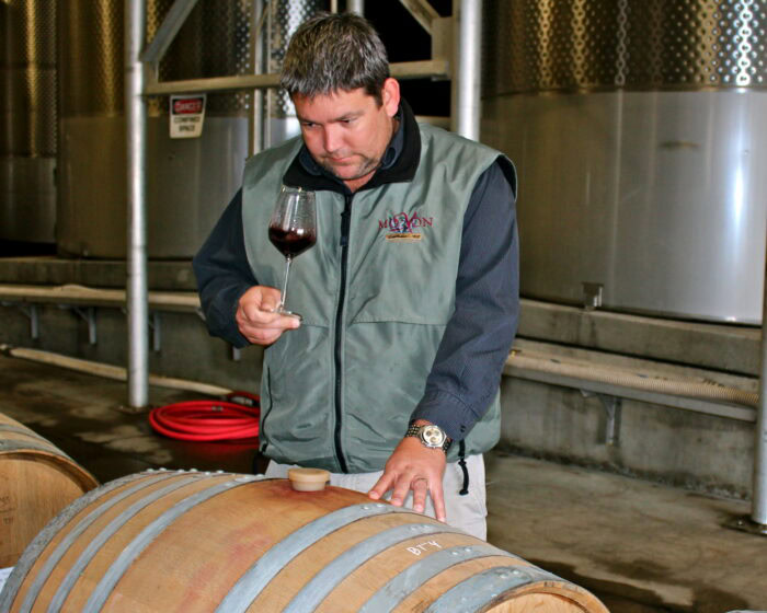 Winemaker inspecting wine in a barrel at a winery in Lodi, California.