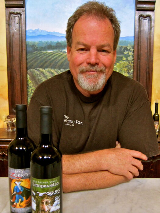 Portrait of a man with wine bottles, vineyard background, promoting Lodi wine industry.