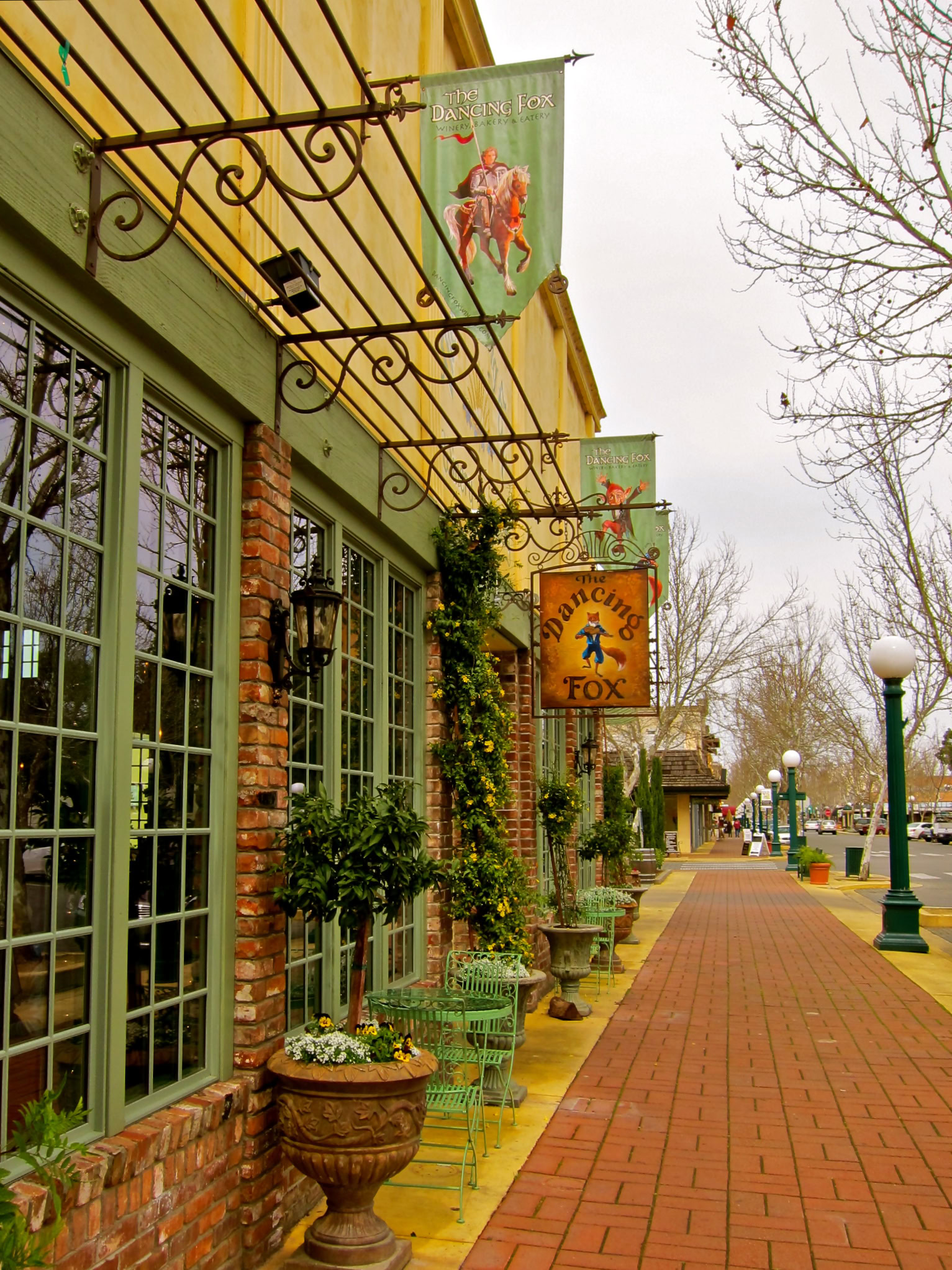 Exterior view of the Lodi Winegrape Commission building with banners and potted plants along the sidewalk.