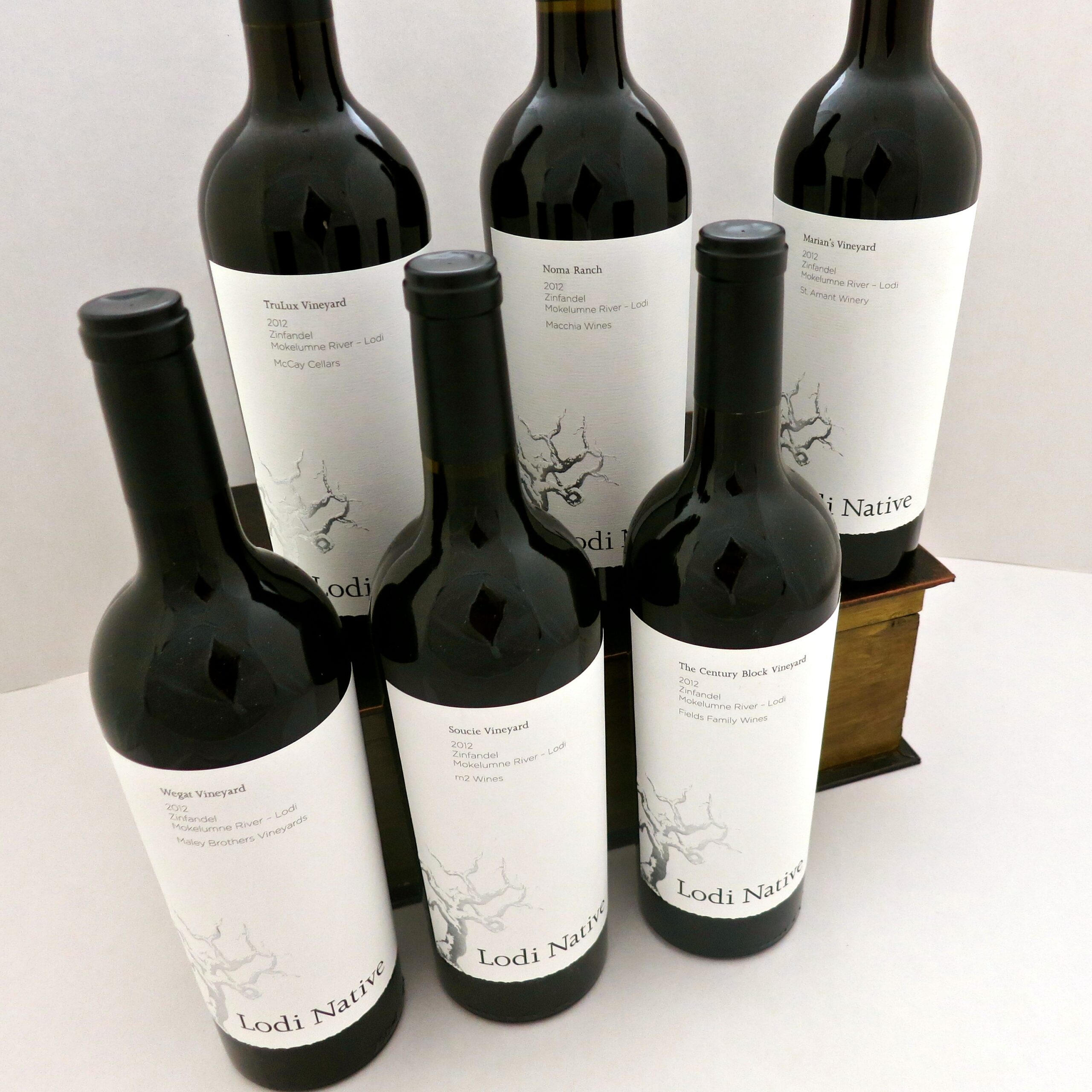 Five wine bottles from Lodi Winegrape Commission with minimalist labels and black caps, displayed on a white background.