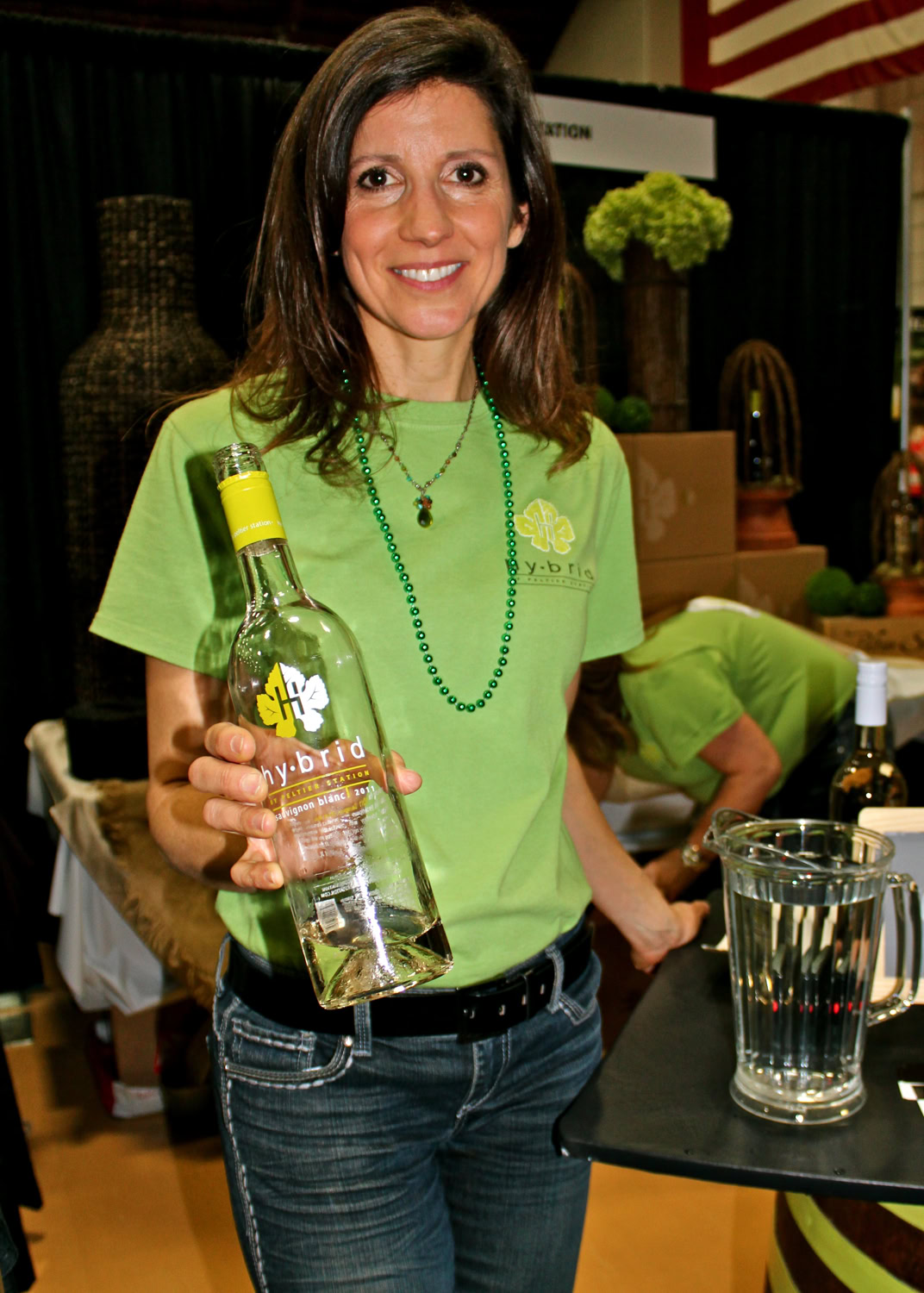 Woman holding a wine bottle at a Lodi Winegrape Commission event, promoting local wine and grape industry.